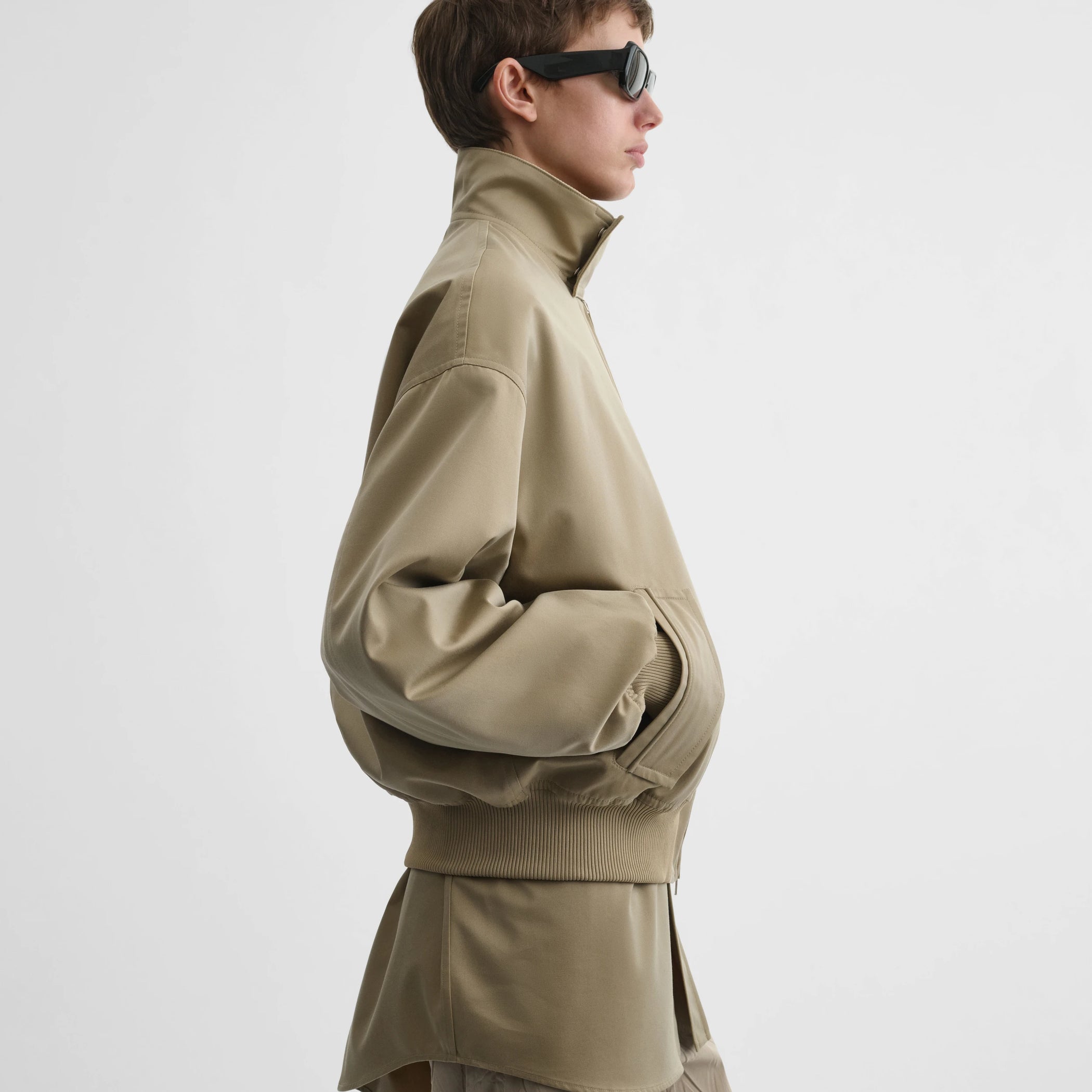 Side view of model wearing golf jacket in trench cotton.