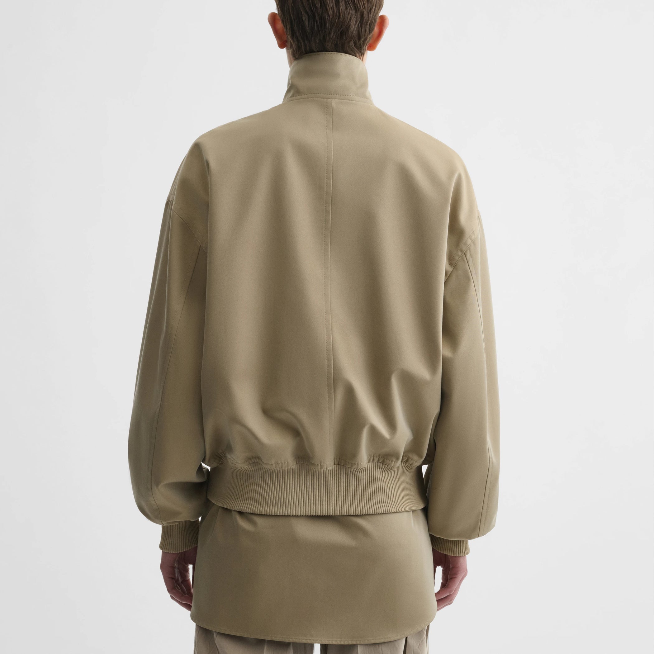 Back view of model wearing golf jacket in trench cotton.