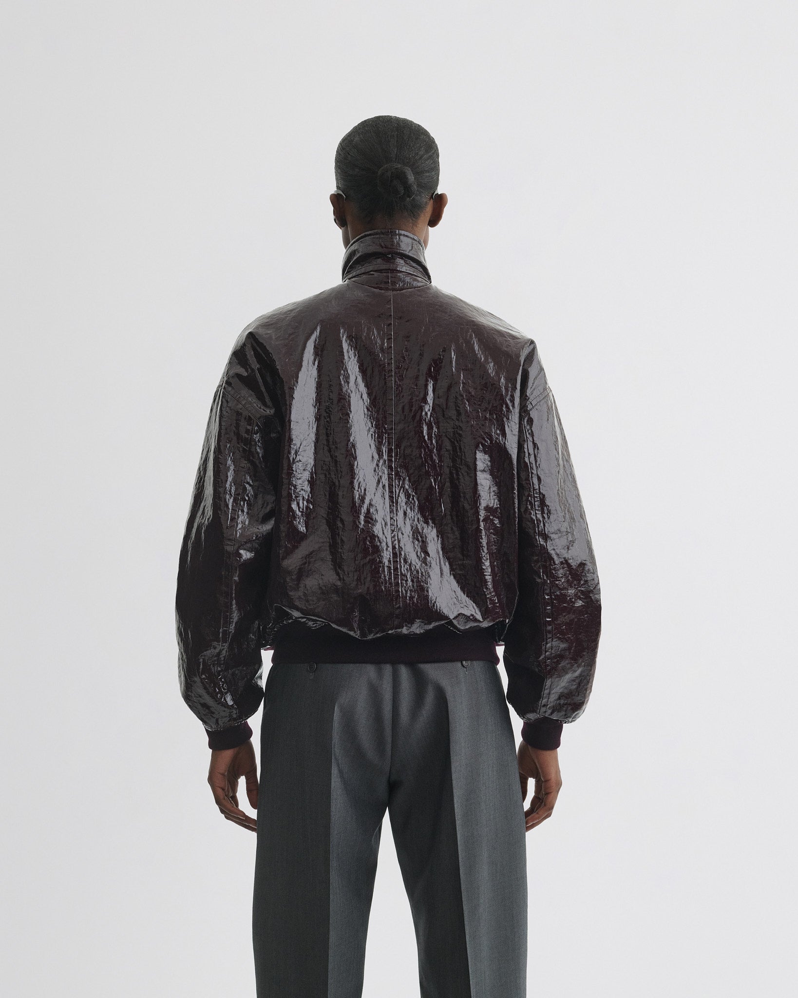 Back view of model wearing golf jacket in burgundy linen canvas.