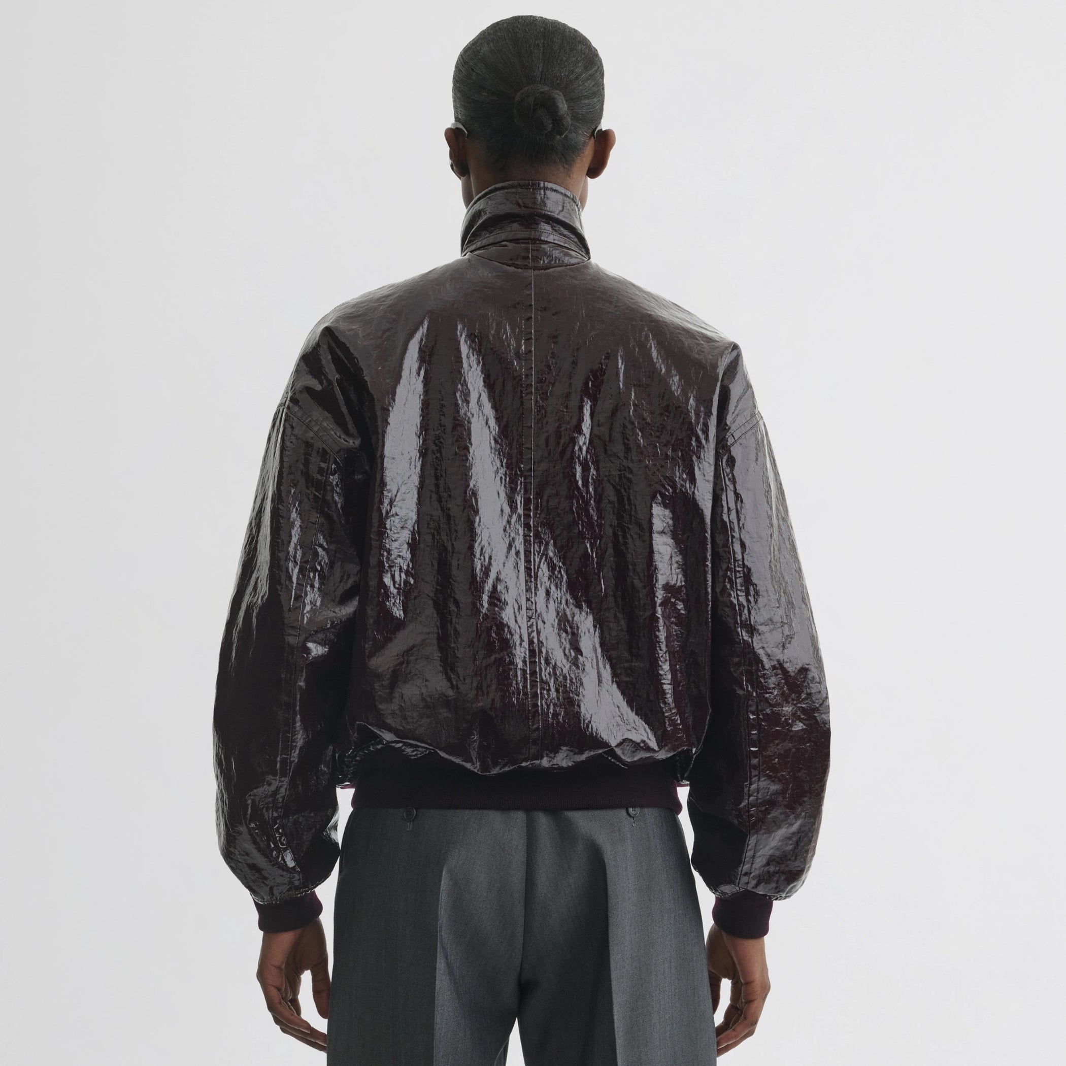 Back view of model wearing golf jacket in burgundy linen canvas.