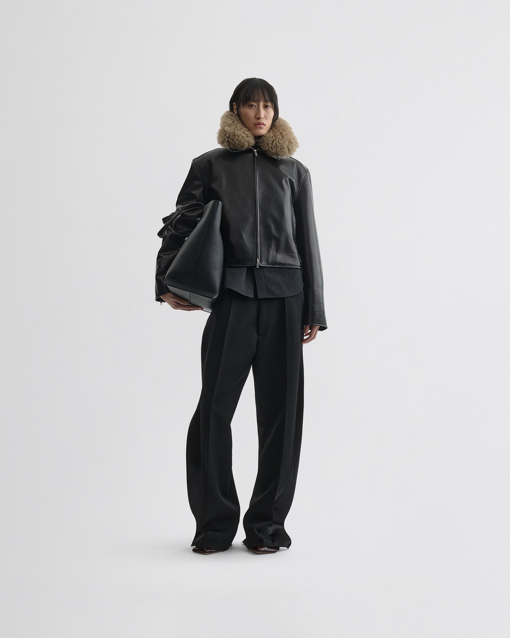 Front full view of model wearing cropped aviator jacket in black leather