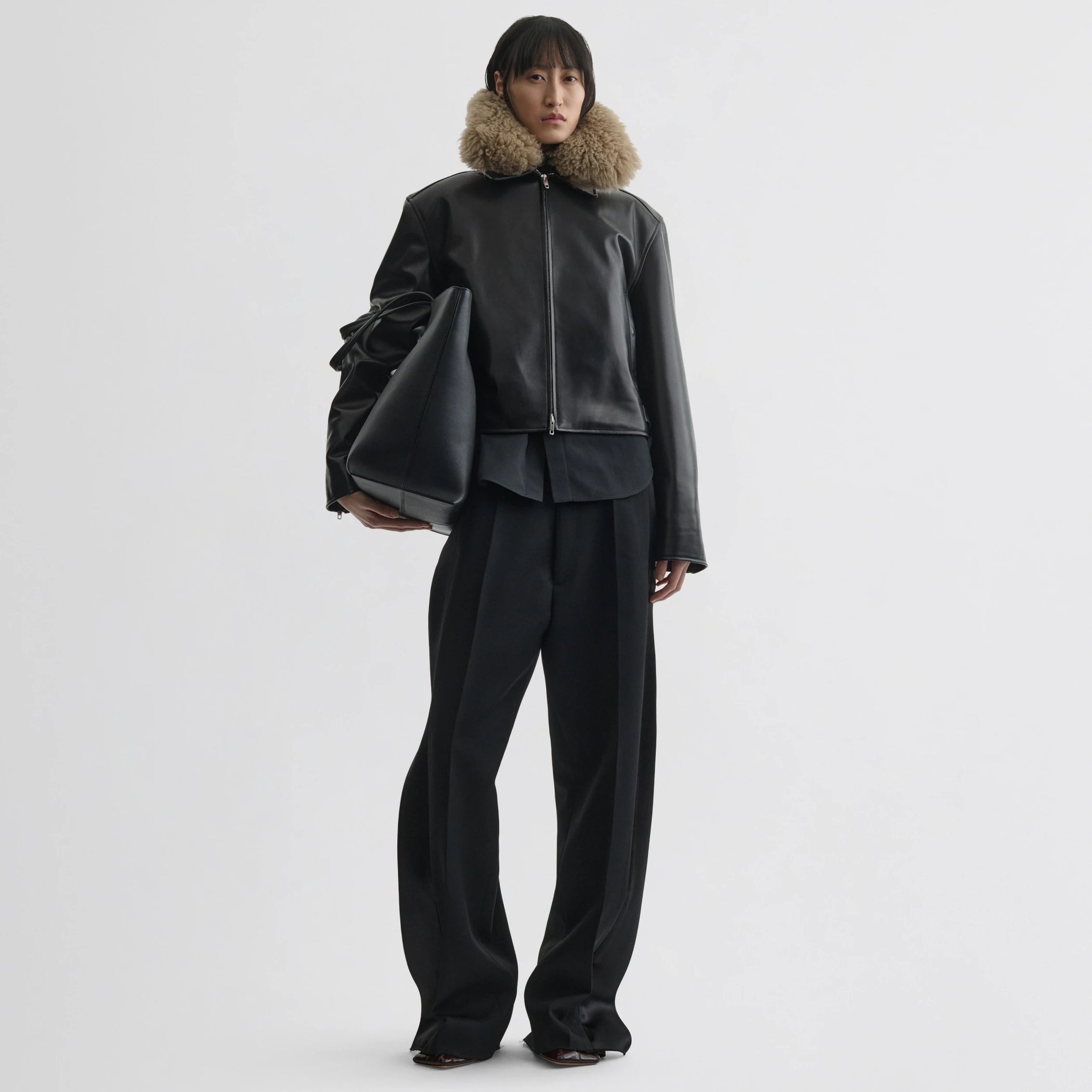 Front view of model wearing cropped aviator jacket in black leather.