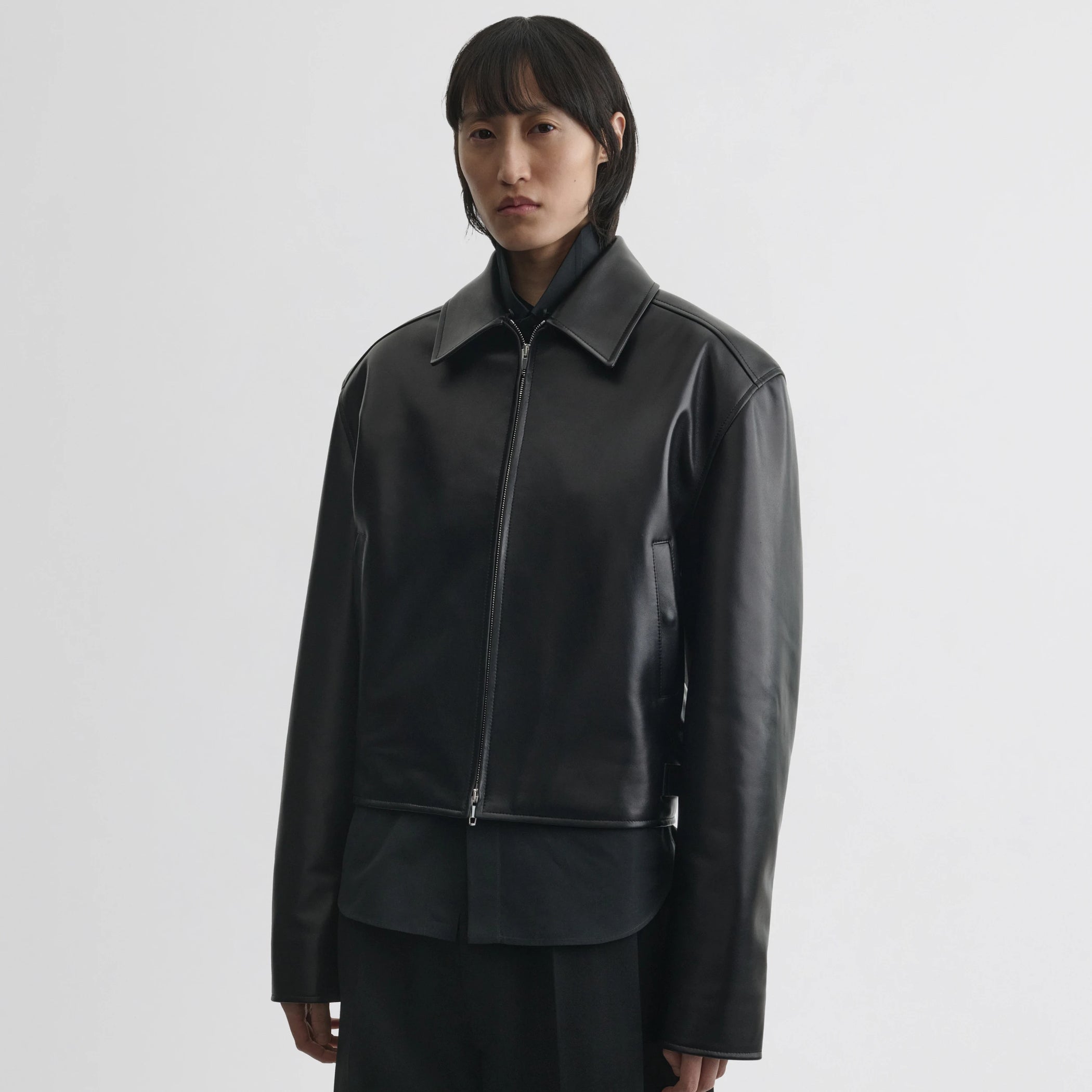 Front view of model wearing cropped aviator jacket in black leather.