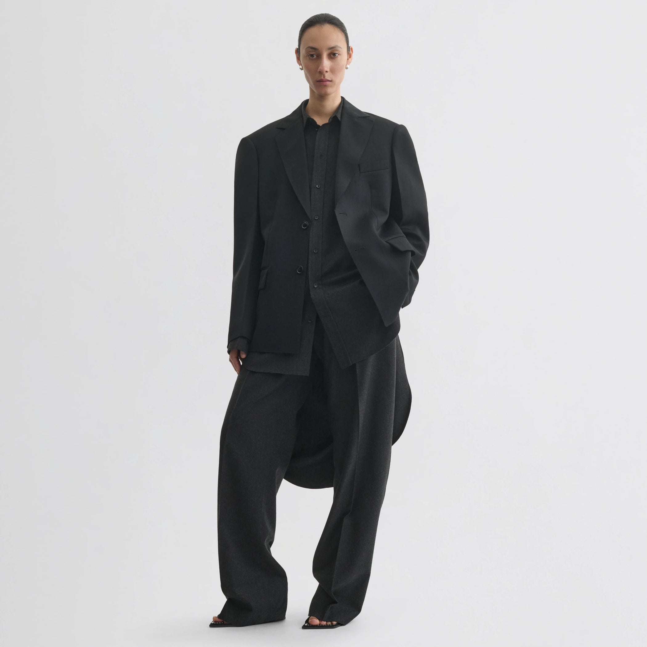 Front view of model wearing tuxedo jacket in black wool.