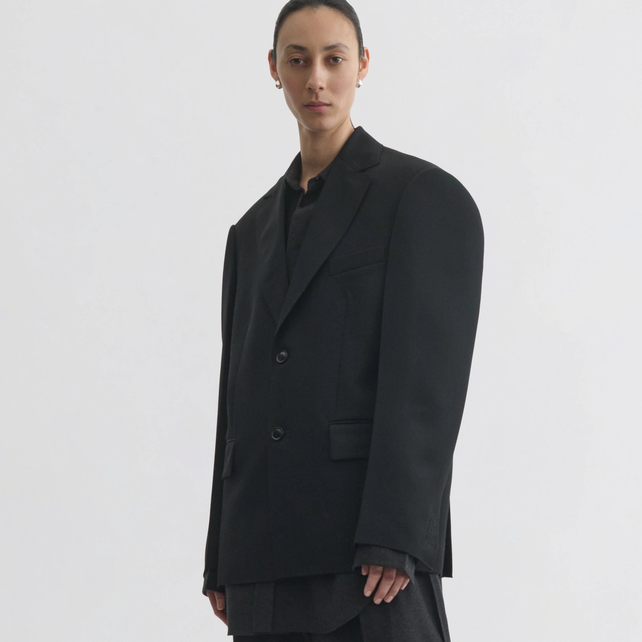 Front view of model wearing tuxedo jacket in black wool.