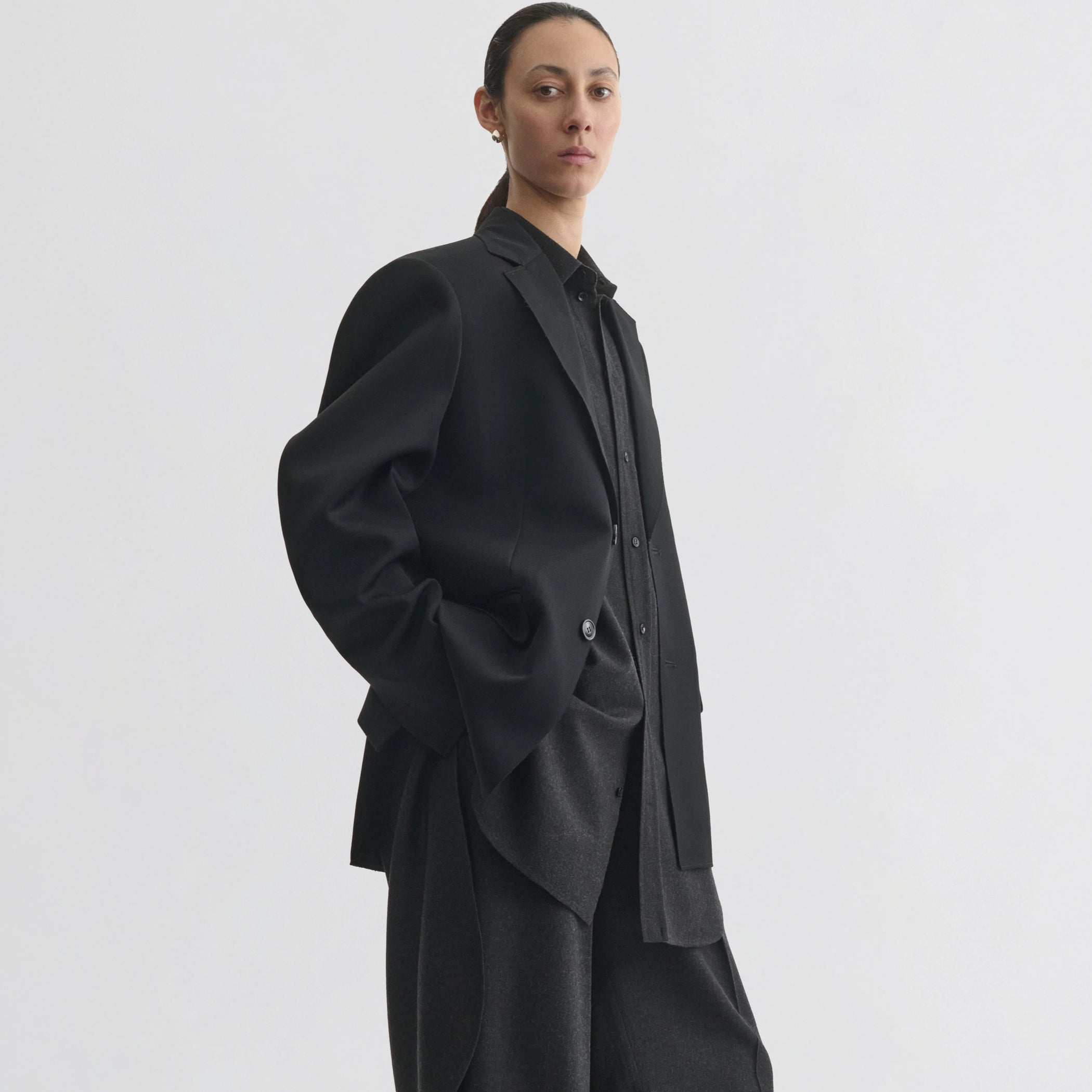Side view of model wearing tuxedo jacket in black wool.