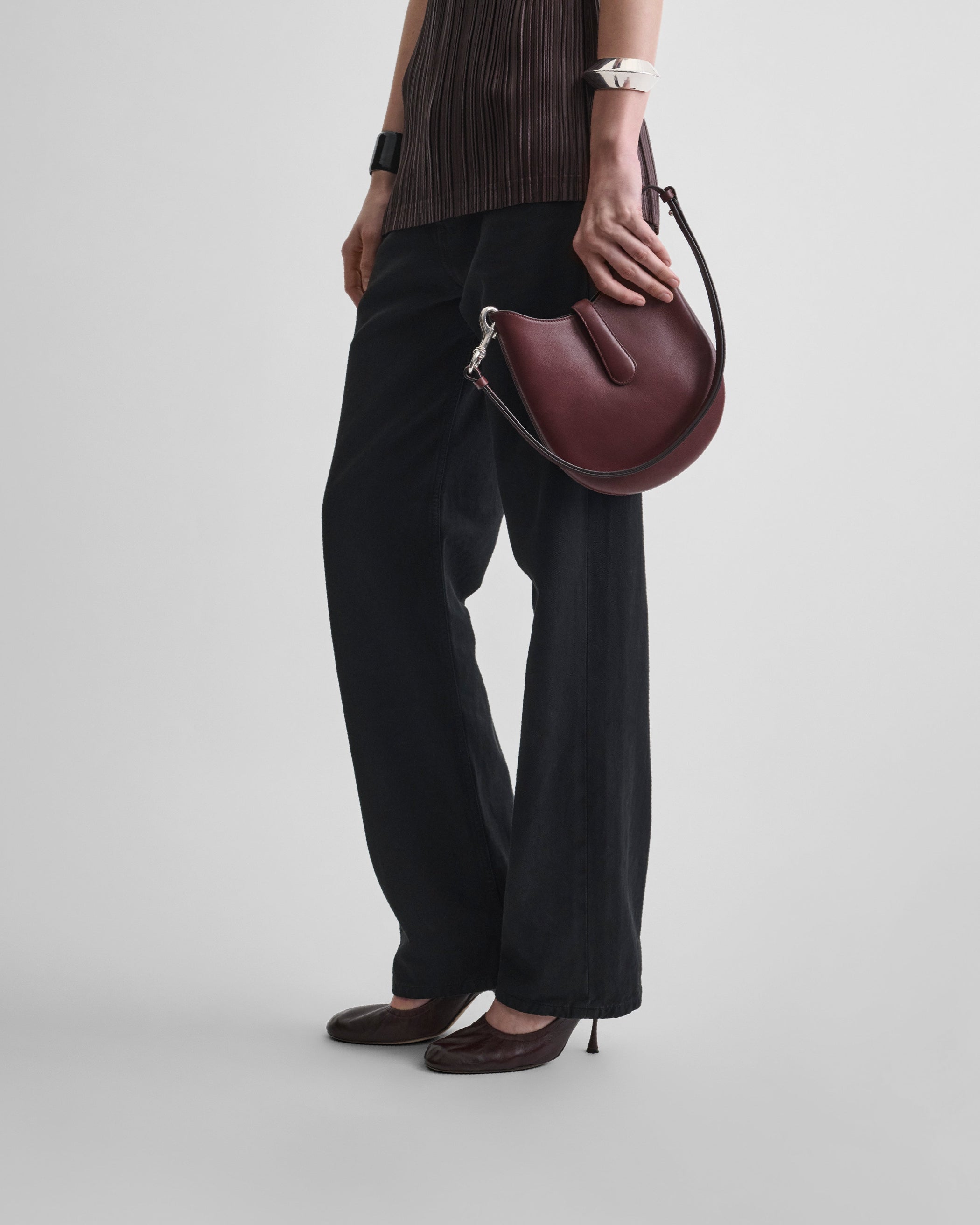 Model holding MINI BEAN SLING in chestnut leather