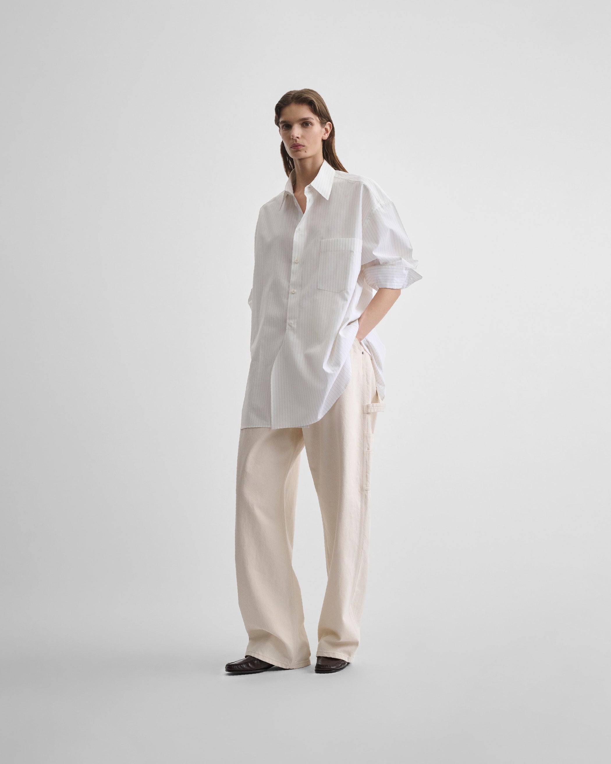 Angled front view of model wearing RELAXED TAILORED SHIRT in white/beige cotton