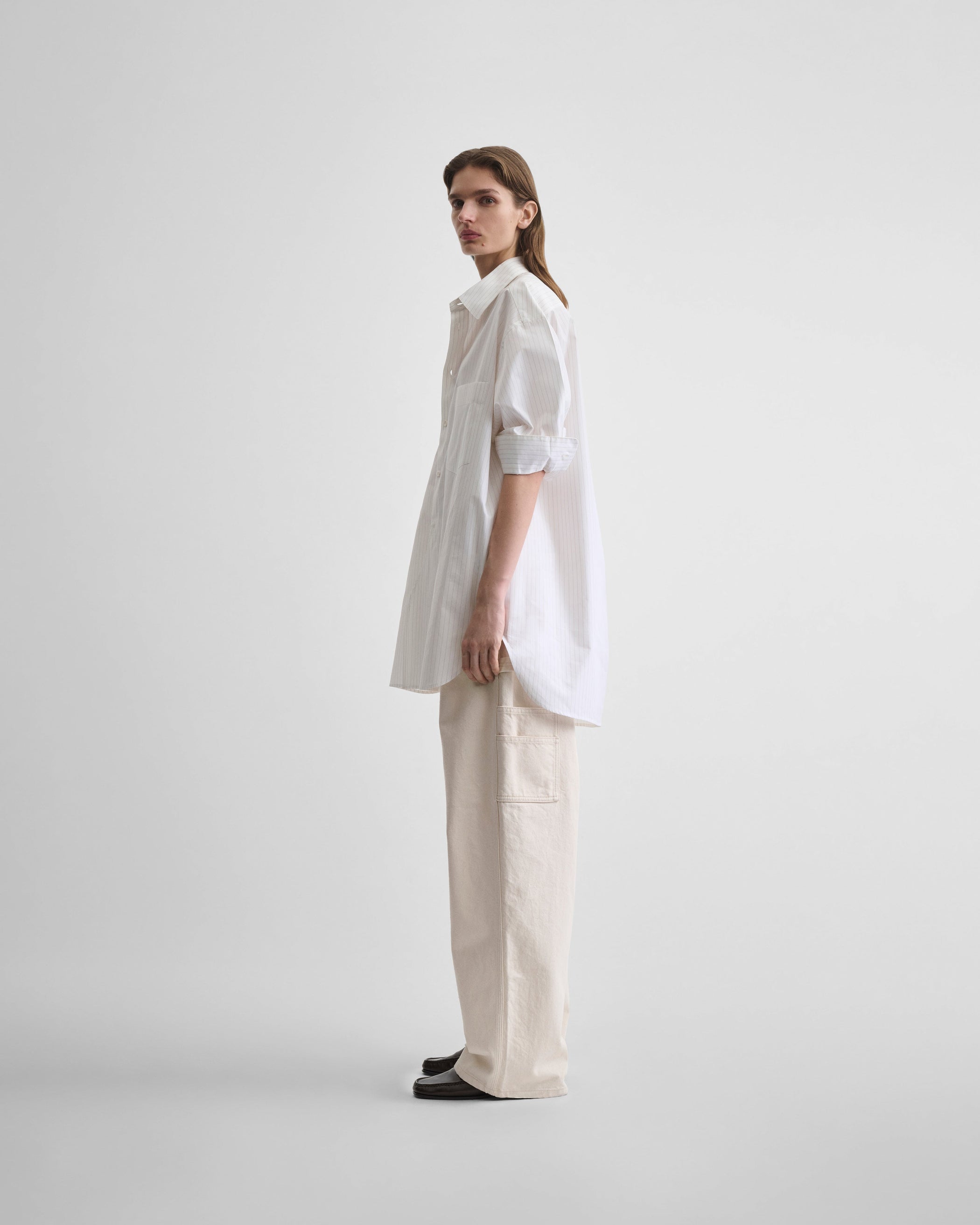 Side view of model wearing RELAXED TAILORED SHIRT in white/beige cotton