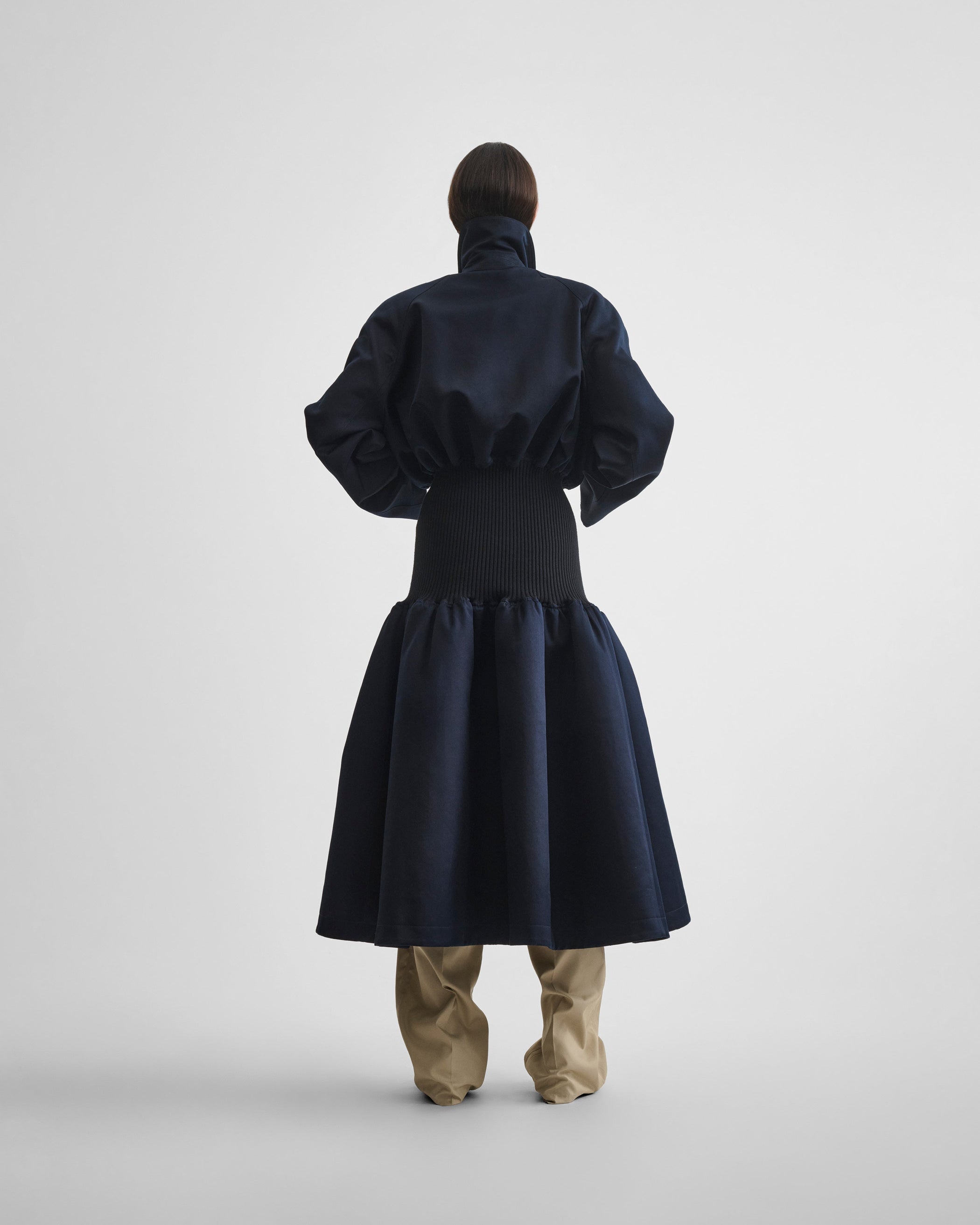 Back view of model wearing KICK COAT in dark navy cotton
