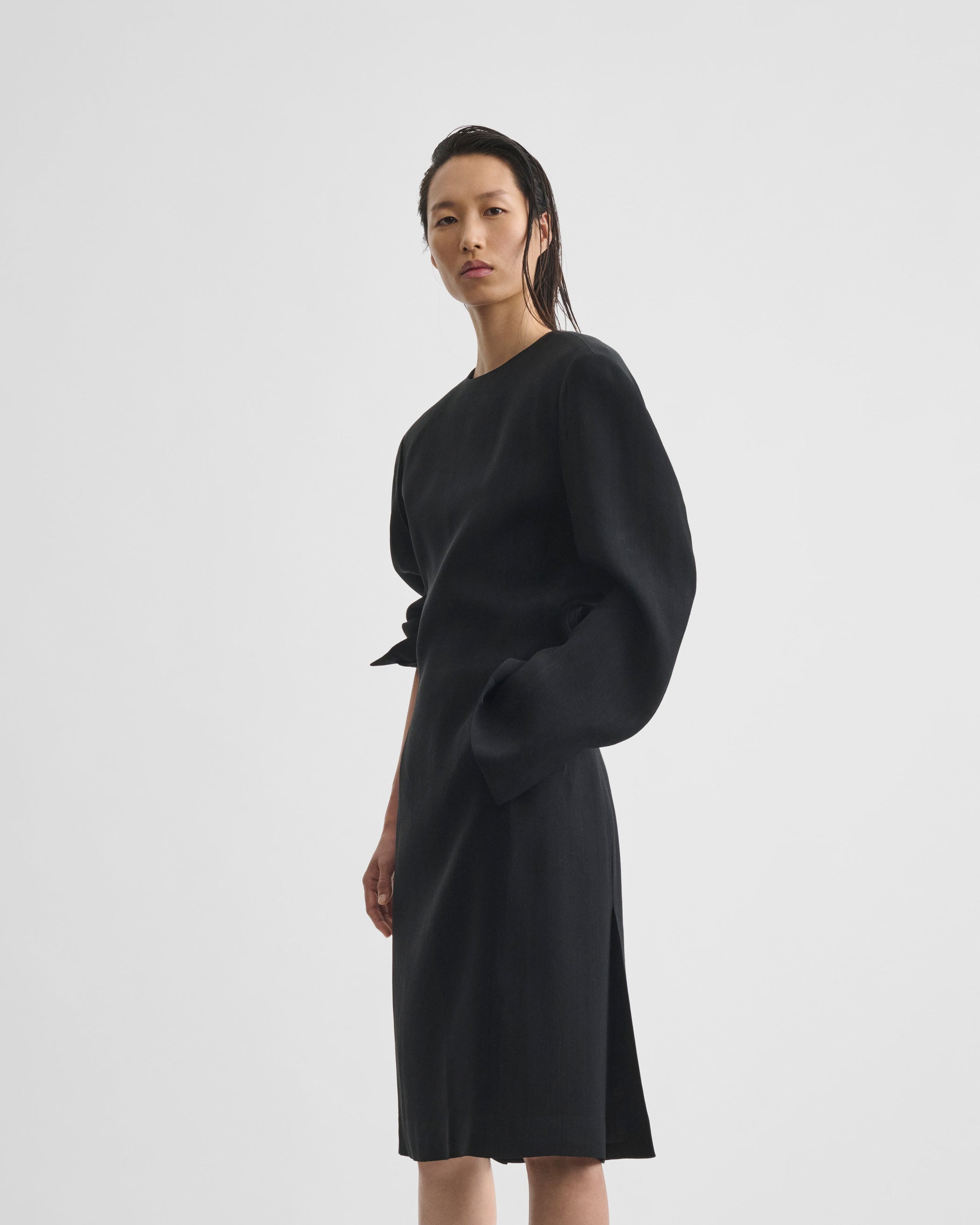 Angled front view of model wearing KINKED TAILORED DRESS in black viscose