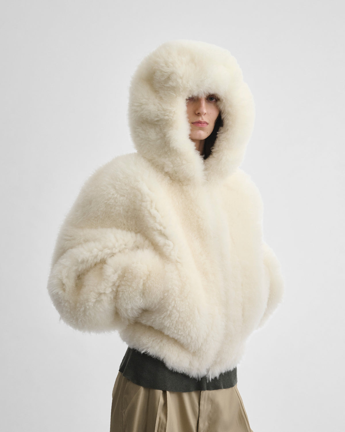Angled front view of model wearing SUPER TEDDY HOODIE in ivory shearling