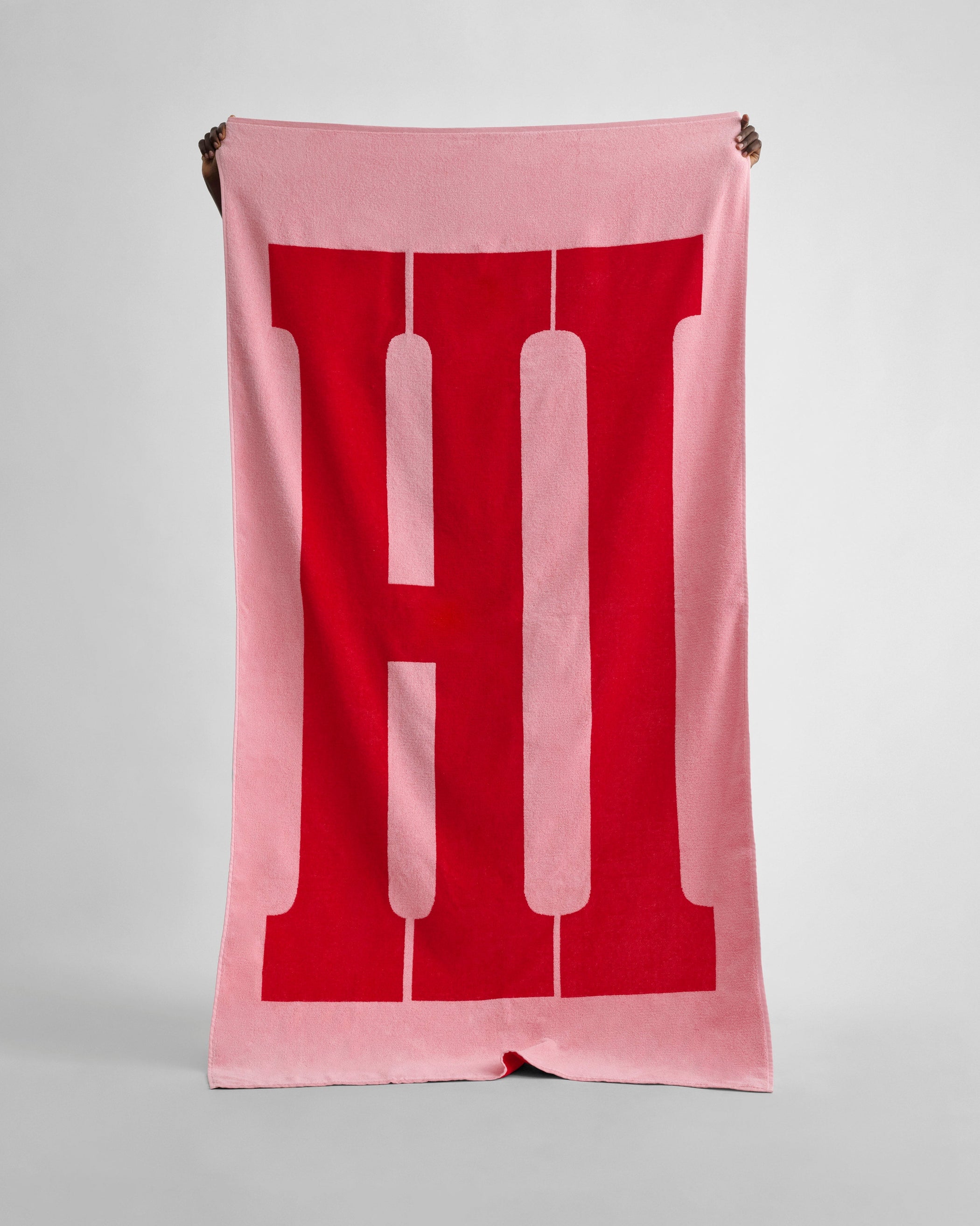 Front view of model holding HI TOWEL in washed pink cotton