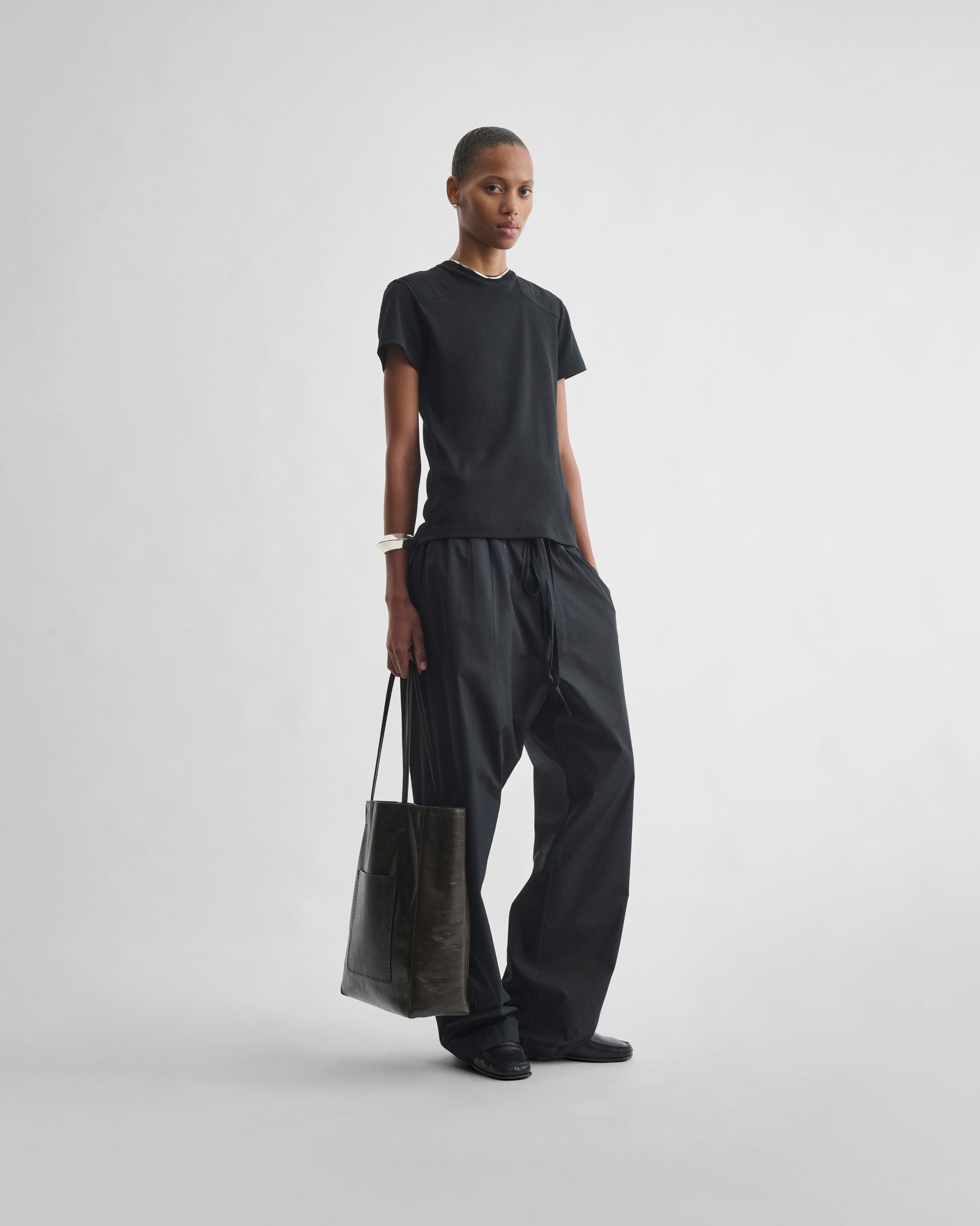 View of model holding PAPER TOTE in chocolate brown leather
