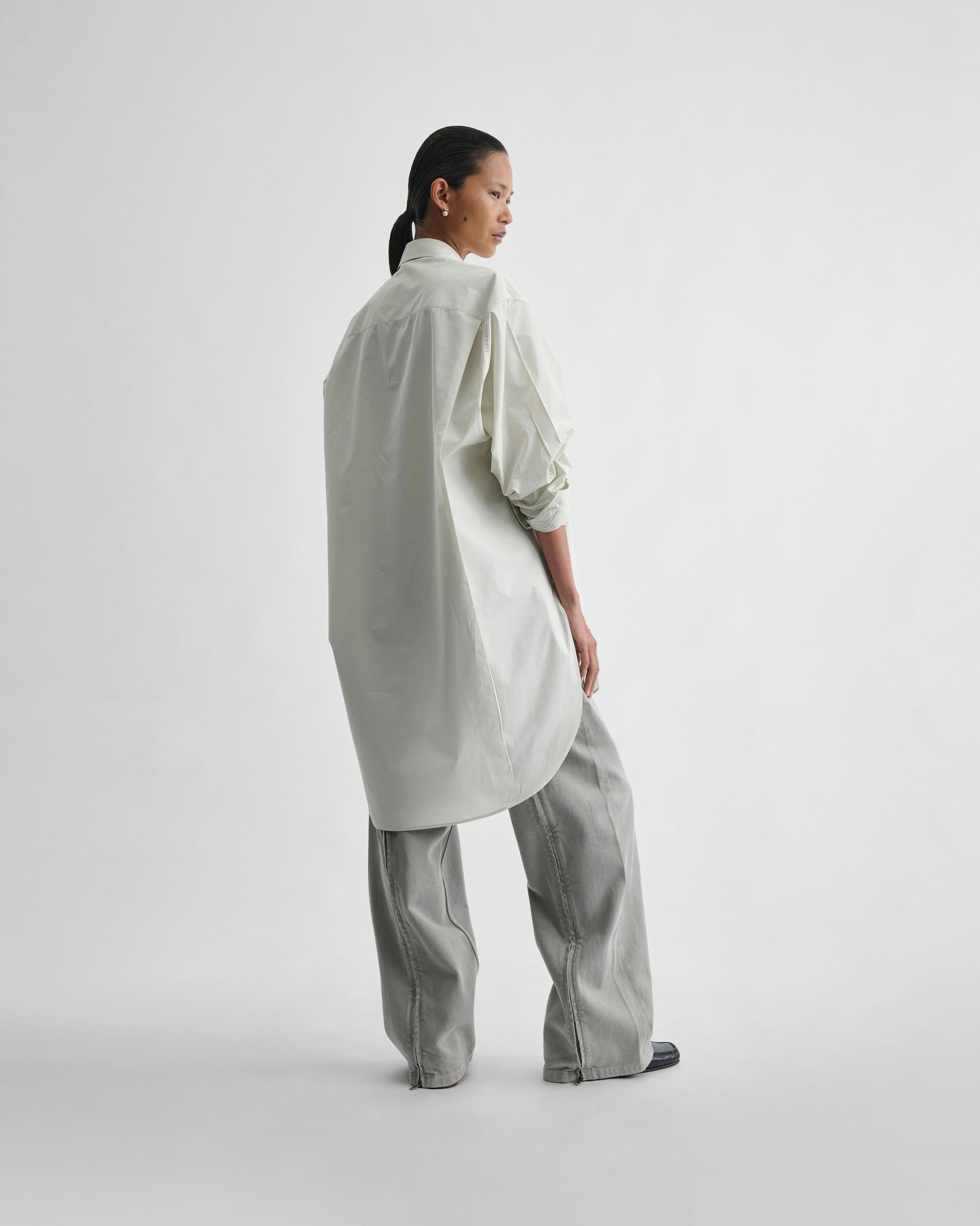 Angled back view of model wearing ELONGATED SHIRT in soft mint cotton