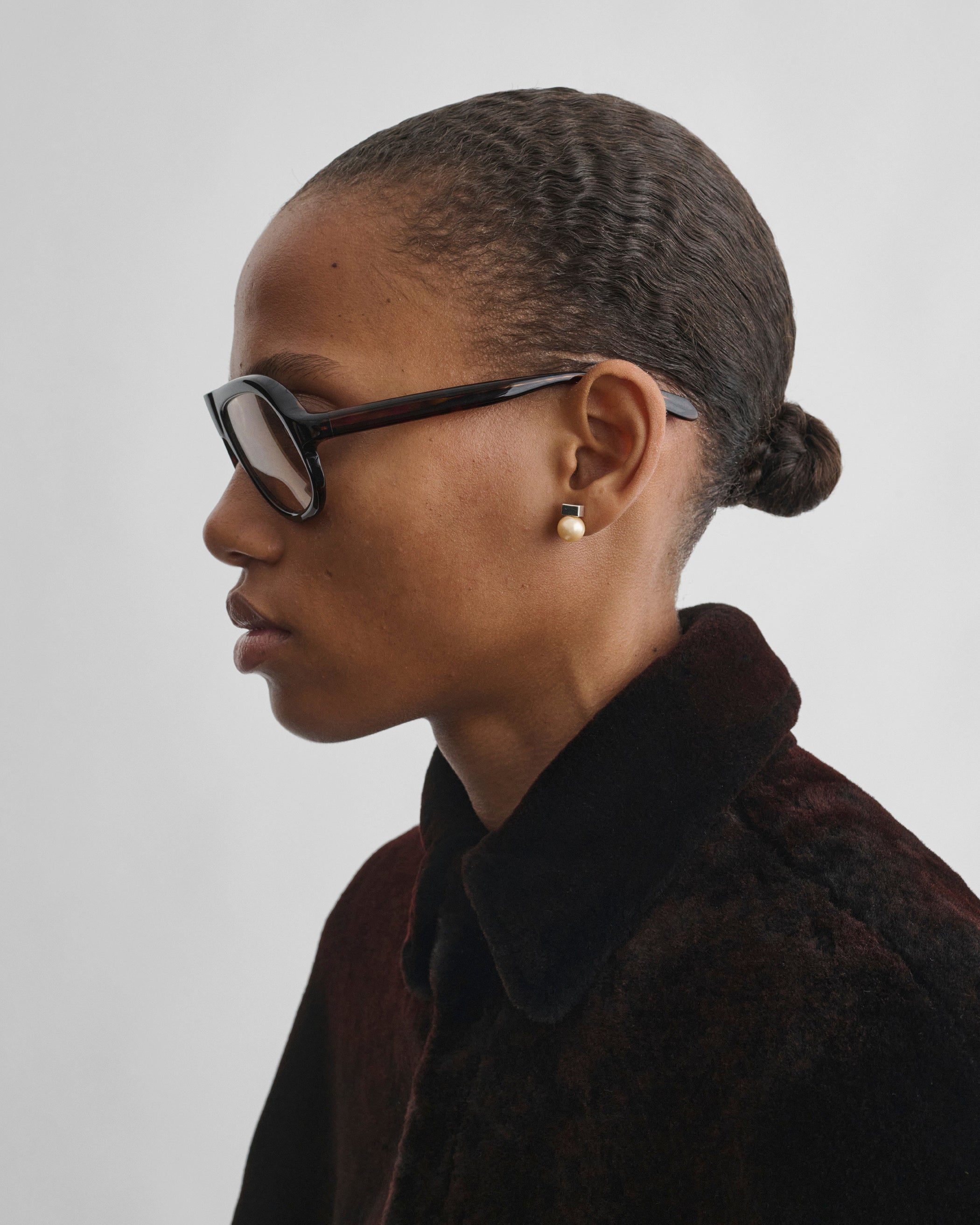 Side view of model wearing PEARL DROP STUDS in gold