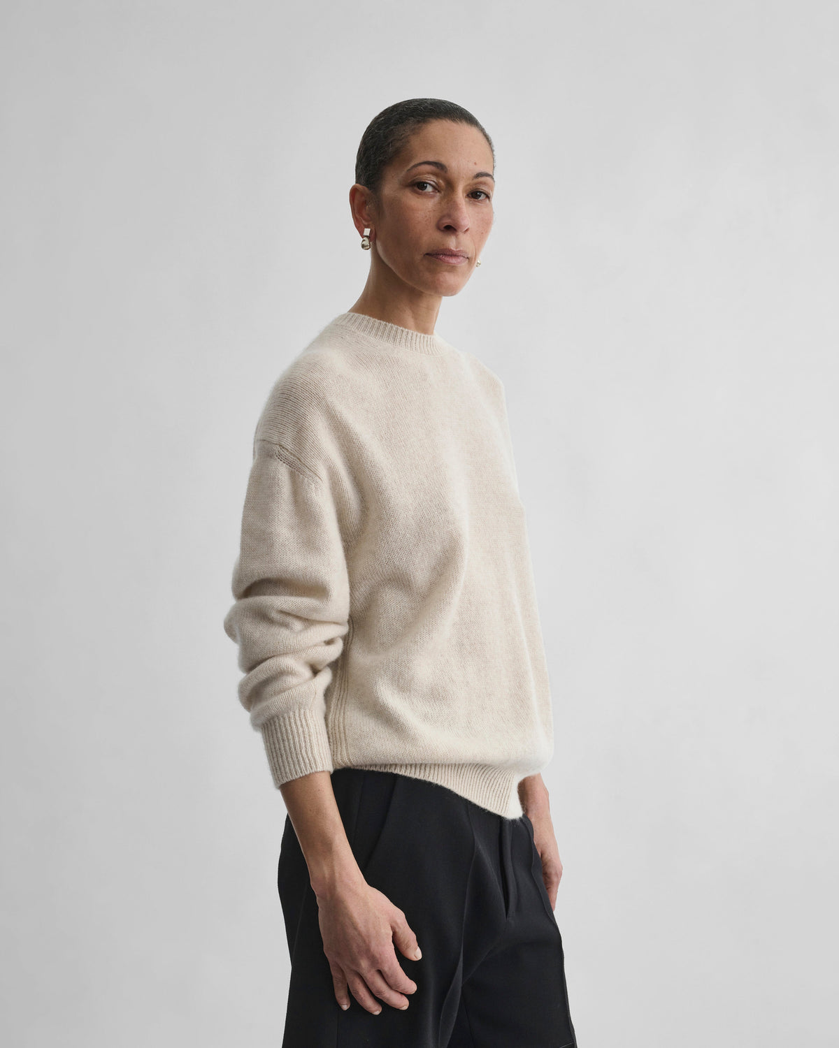 Angled front view of model wearing CREWNECK SWEATER in cream cashmere