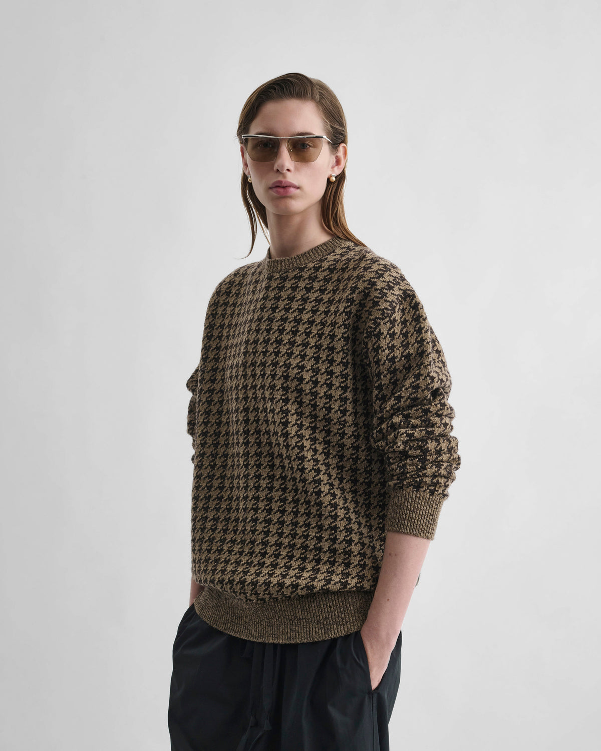 Angled front view of model wearing CREWNECK JACQUARD SWEATER in brown/beige houndstooth