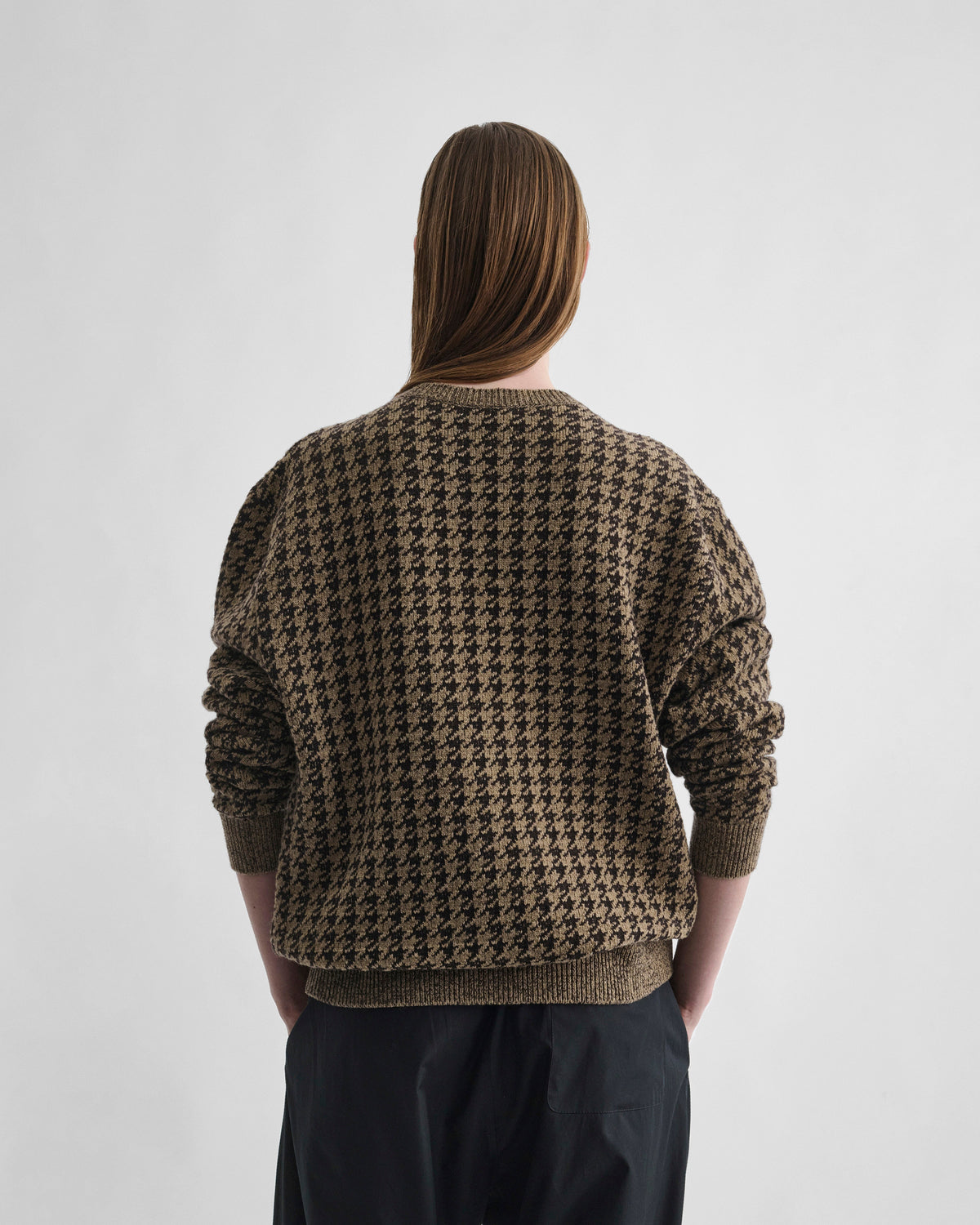 Back view of model wearing CREWNECK JACQUARD SWEATER in brown/beige houndstooth
