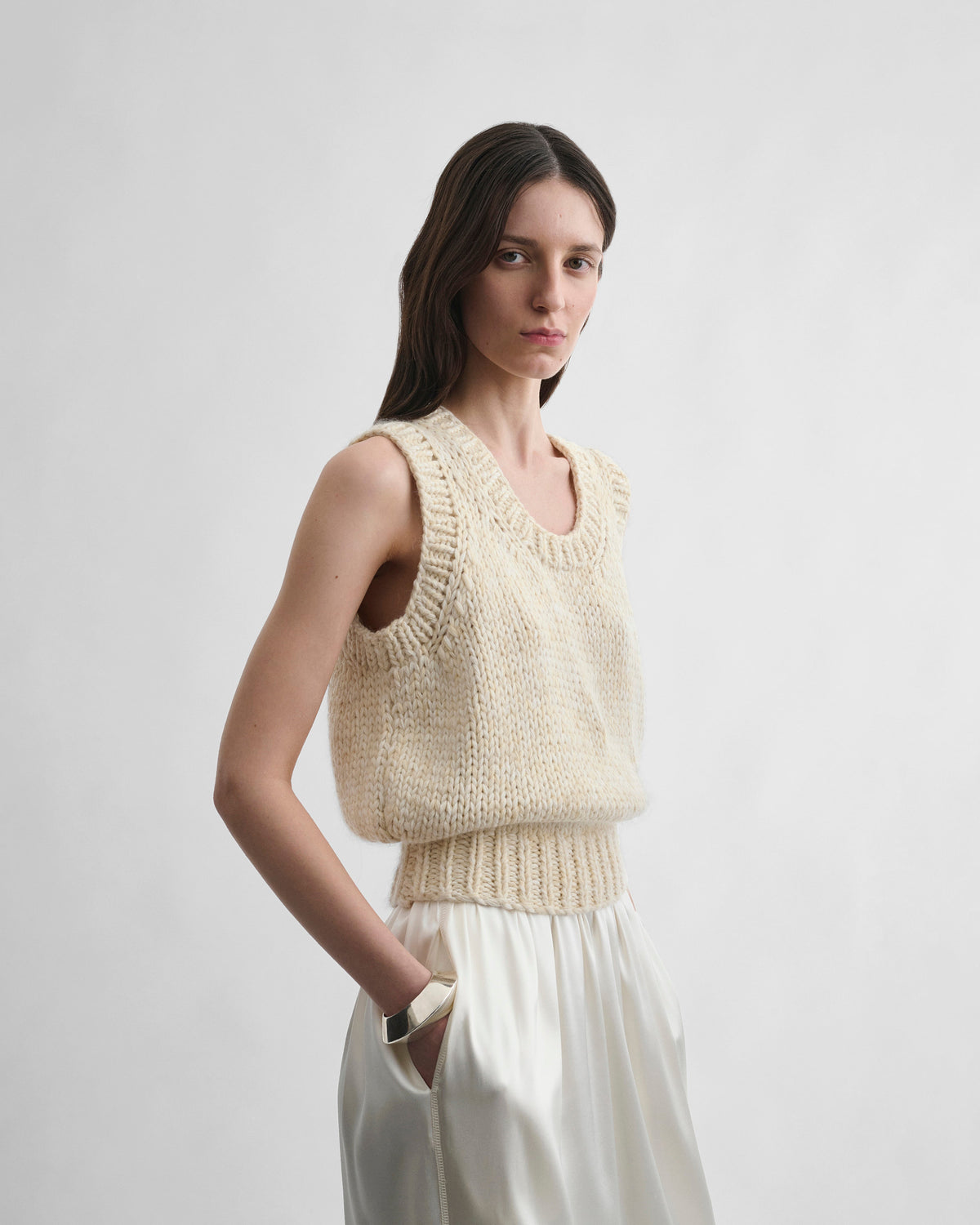 Angled front view of model wearing HANDKNIT VEST in cream wool