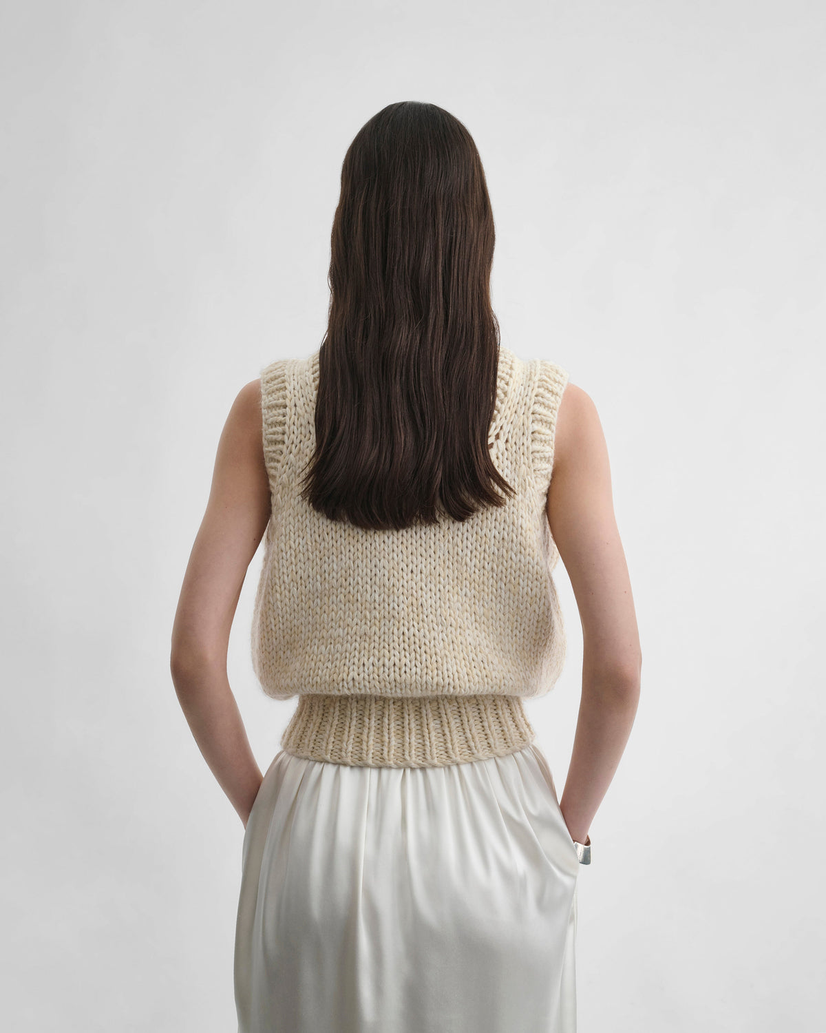 Back view of model wearing HANDKNIT VEST in cream wool