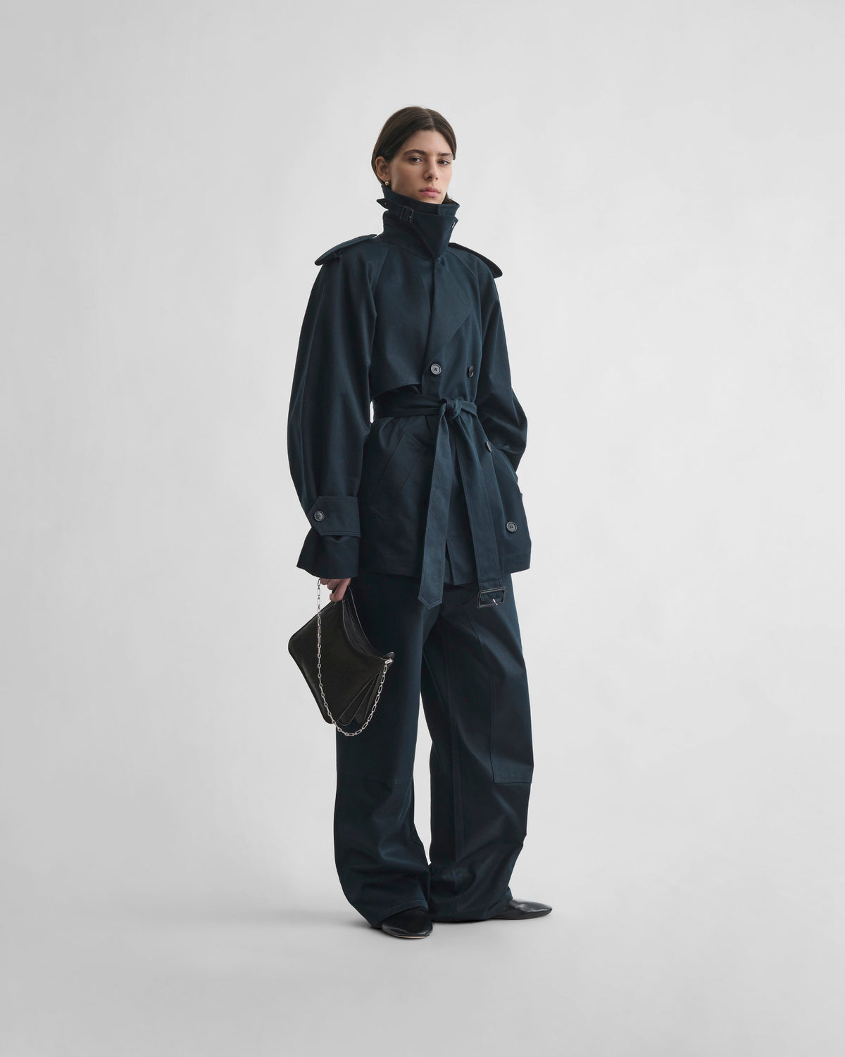 Angled front view of model wearing CROPPED TRENCH in black ink cotton