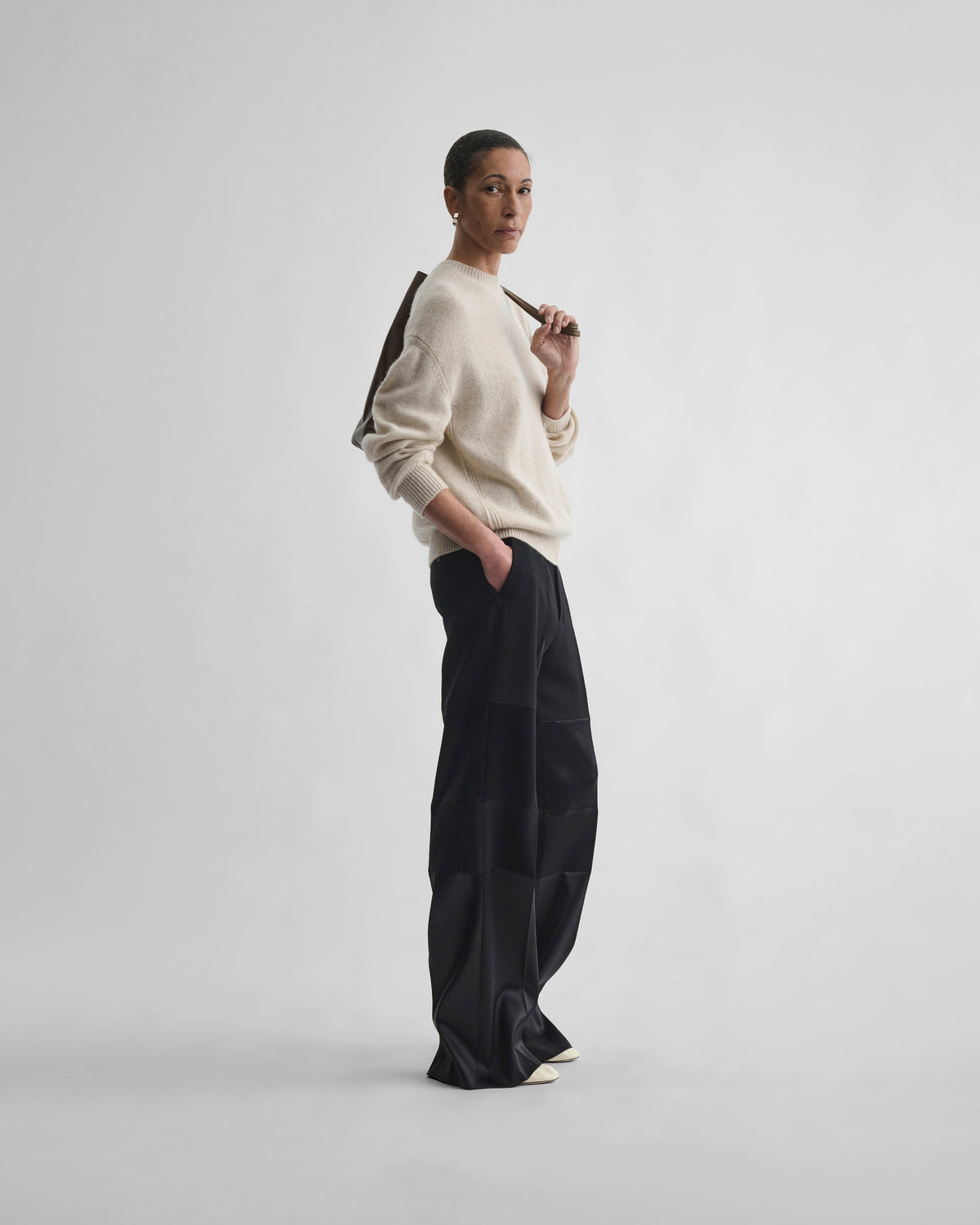 Side view of model wearing STACKED TUX TROUSERS in black wool