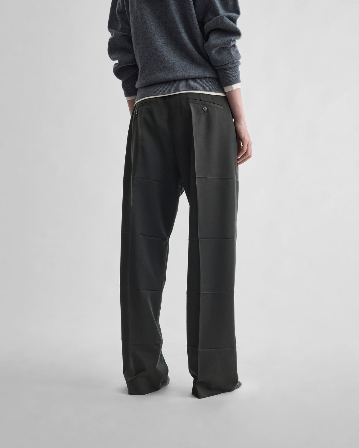 Back view of model wearing PRESSED DROP TROUSERS in green bronze wool