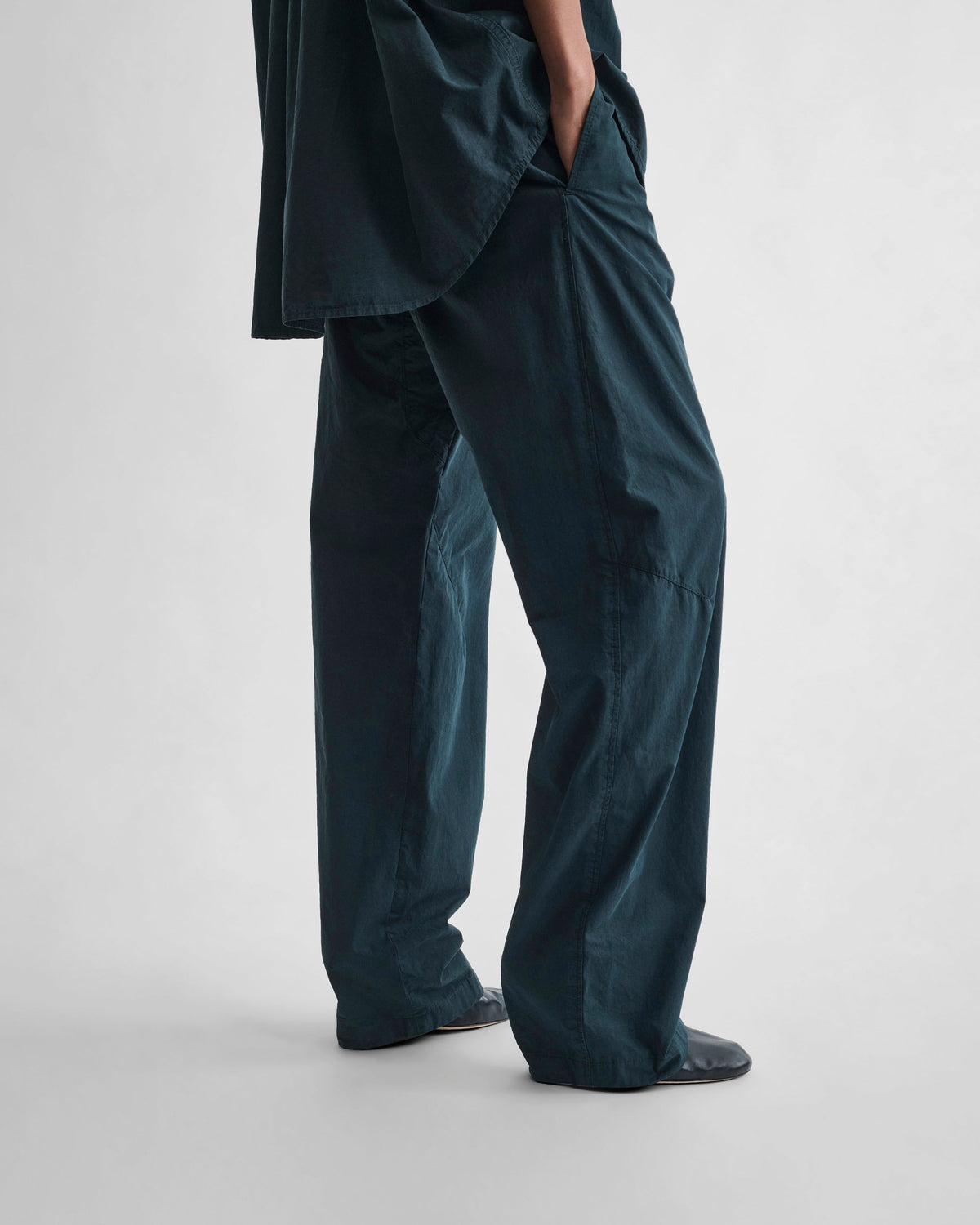 Angled side view of model wearing ARCH TROUSERS in black ink cotton