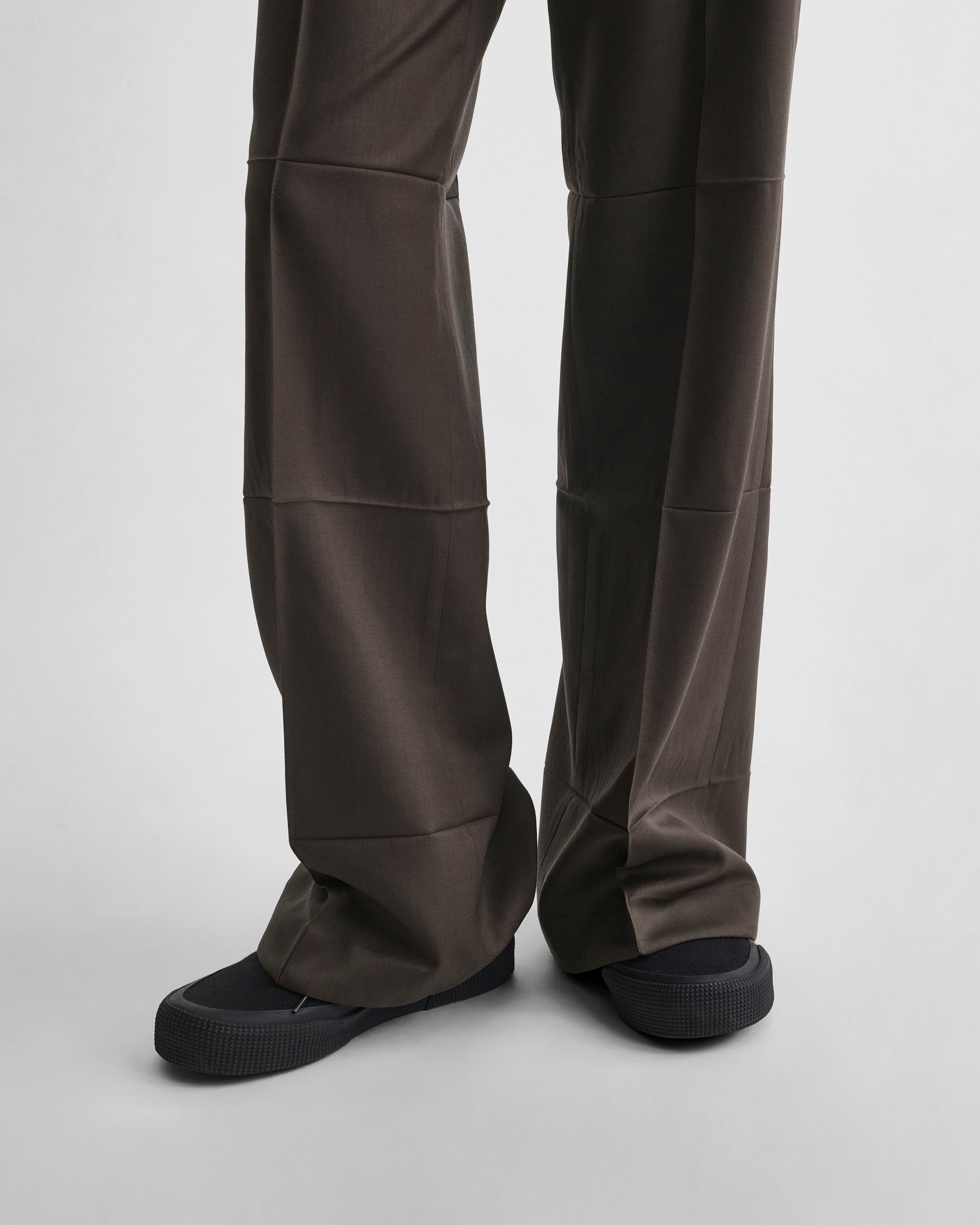 Detail view of model wearing CREASED BOYISH TAILORED TROUSERS in brown khaki wool