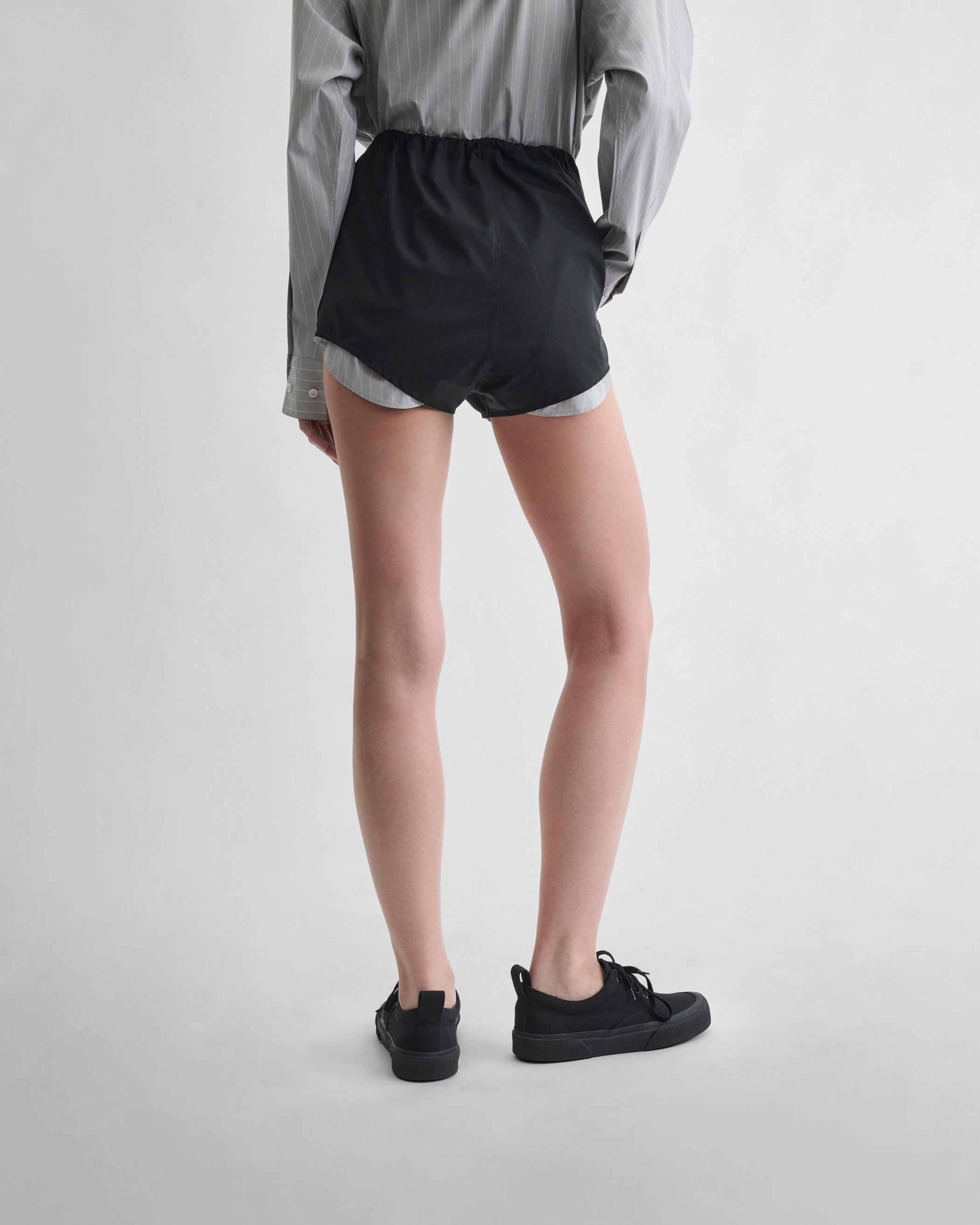 Back view of model wearing HIGH SHORTS in black cotton