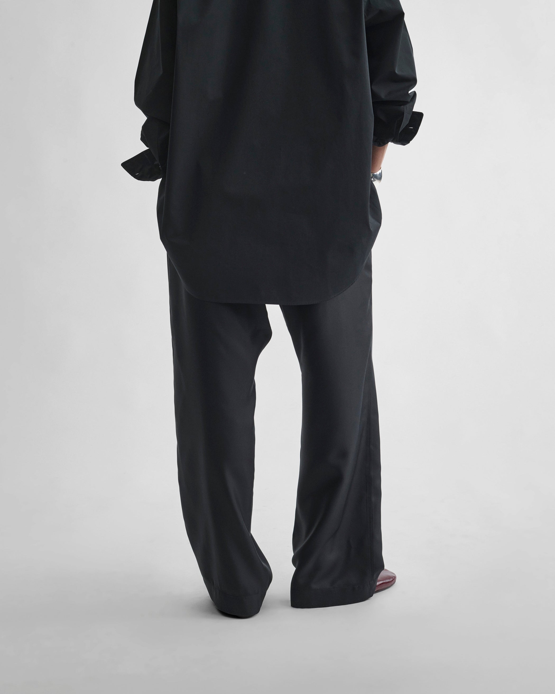 Back view of model wearing PYJAMA TROUSERS in black silk