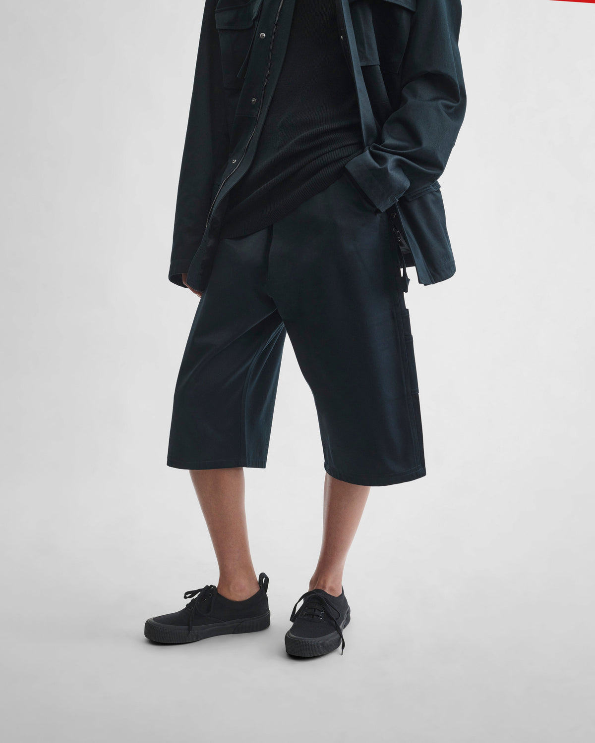 Angled front view of model wearing UTILITY SHORTS in black ink cotton