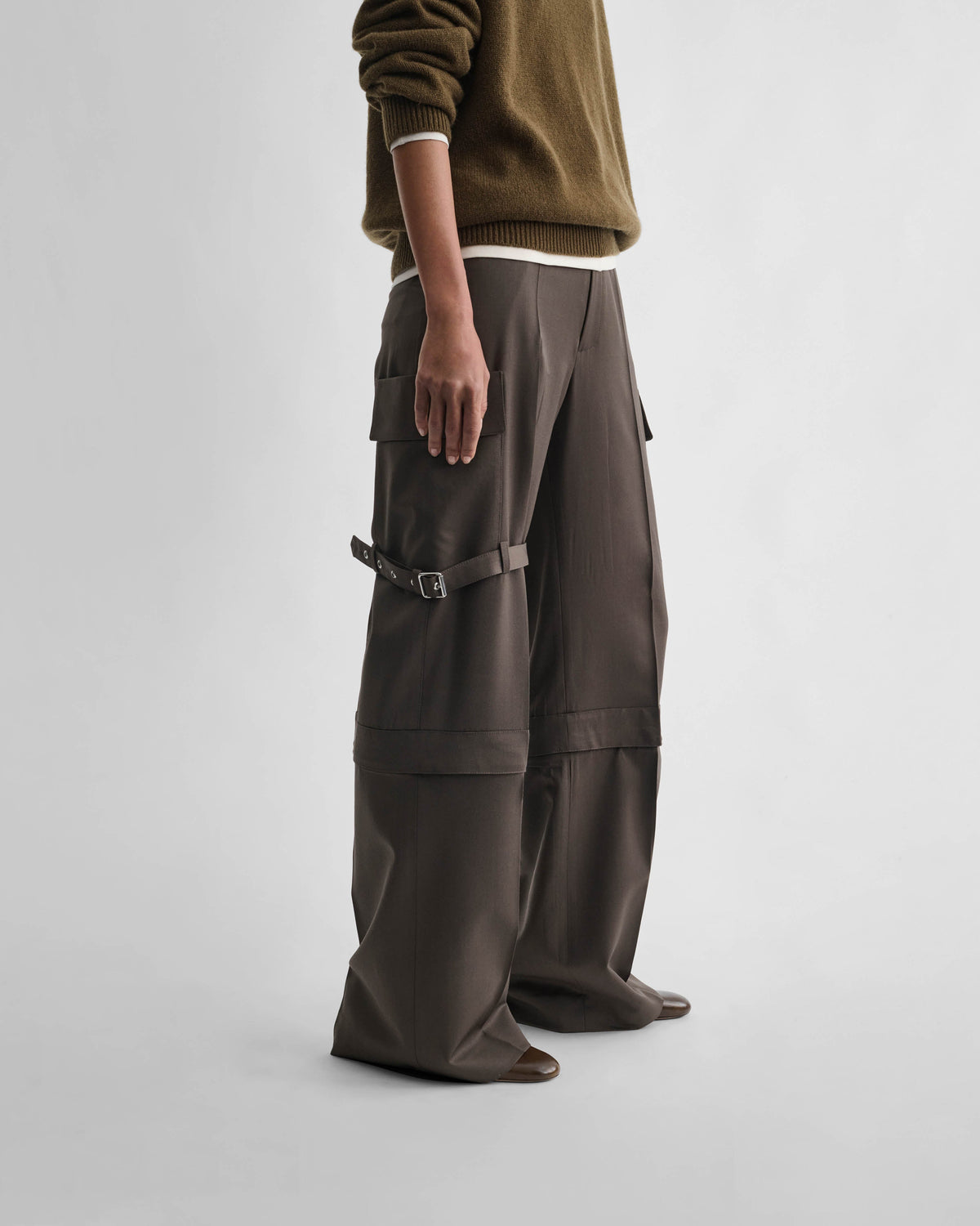 Side view of model wearing STRAP TROUSERS in khaki wool