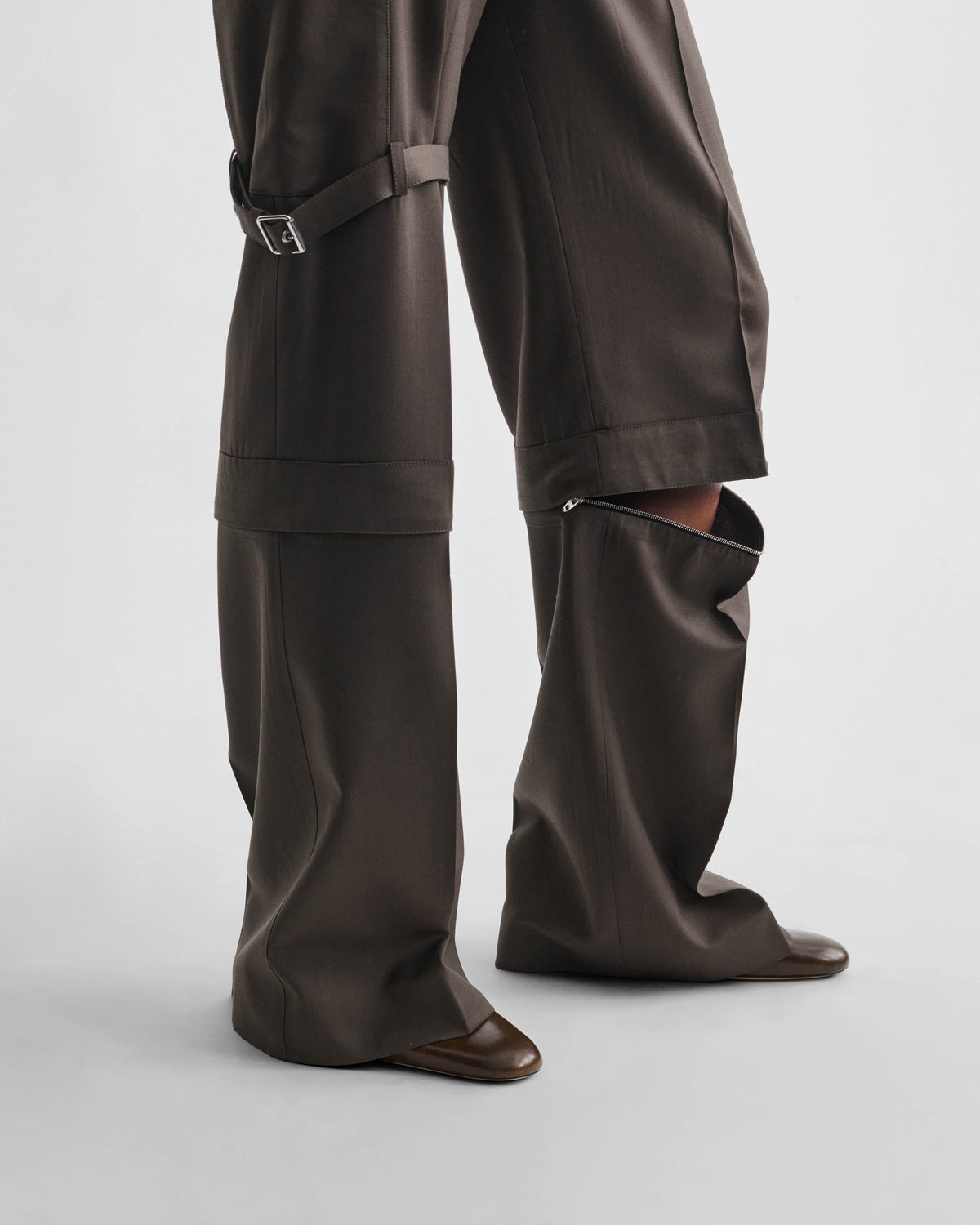 Detail view of model wearing STRAP TROUSERS in brown khaki wool