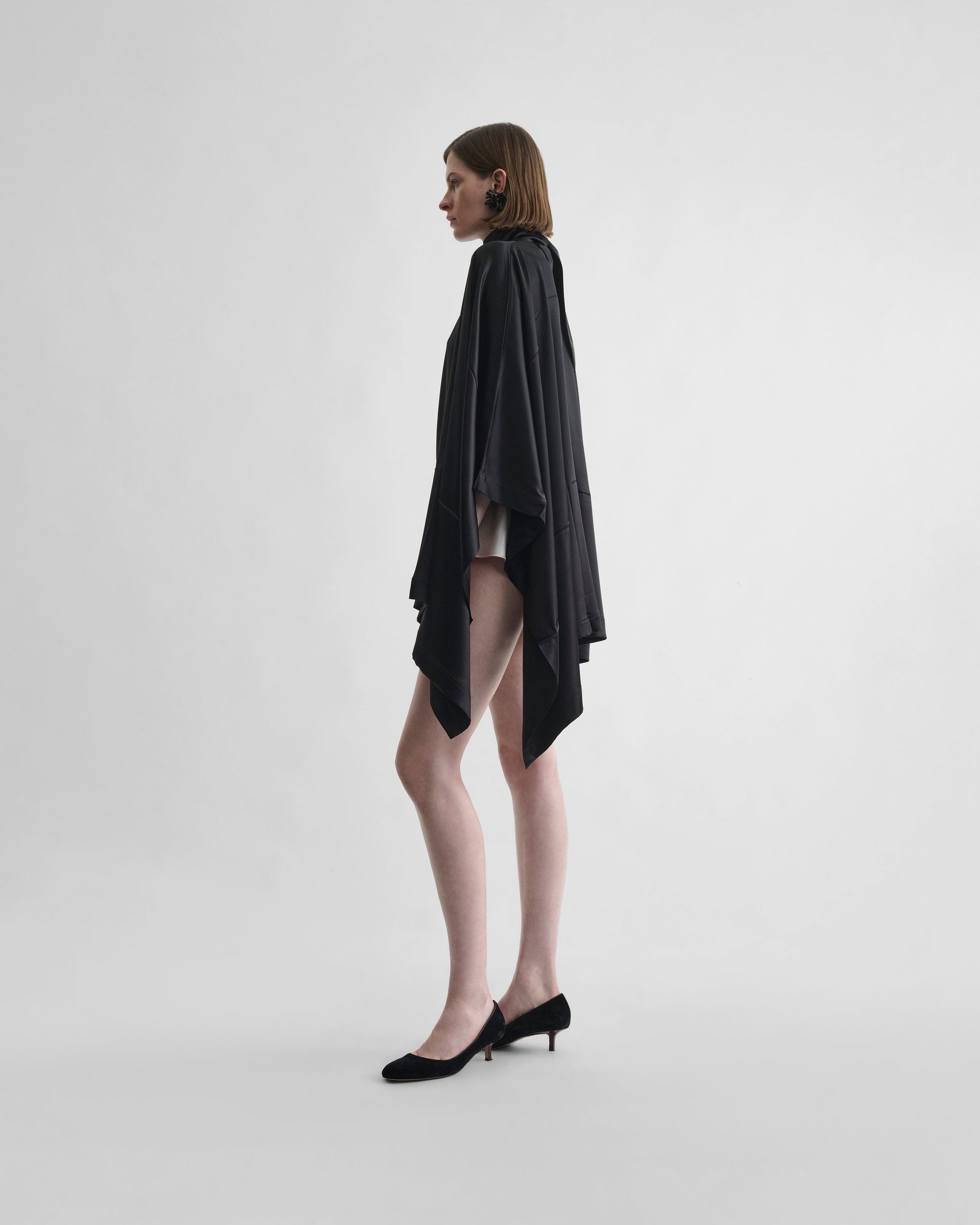 Side view of model wearing CAPED TOP in black silk