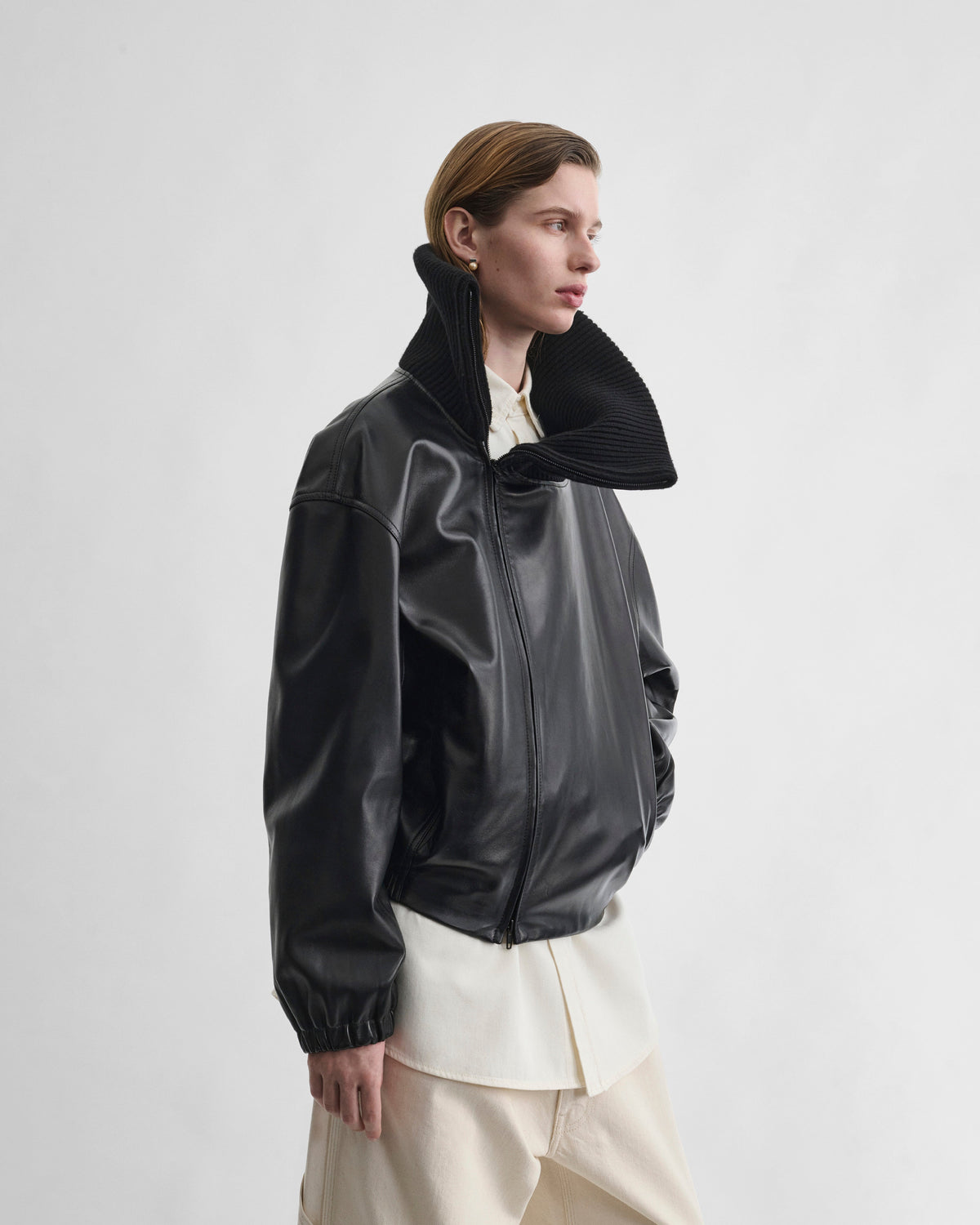 Angled front view of model wearing RIB NECK JACKET in black leather
