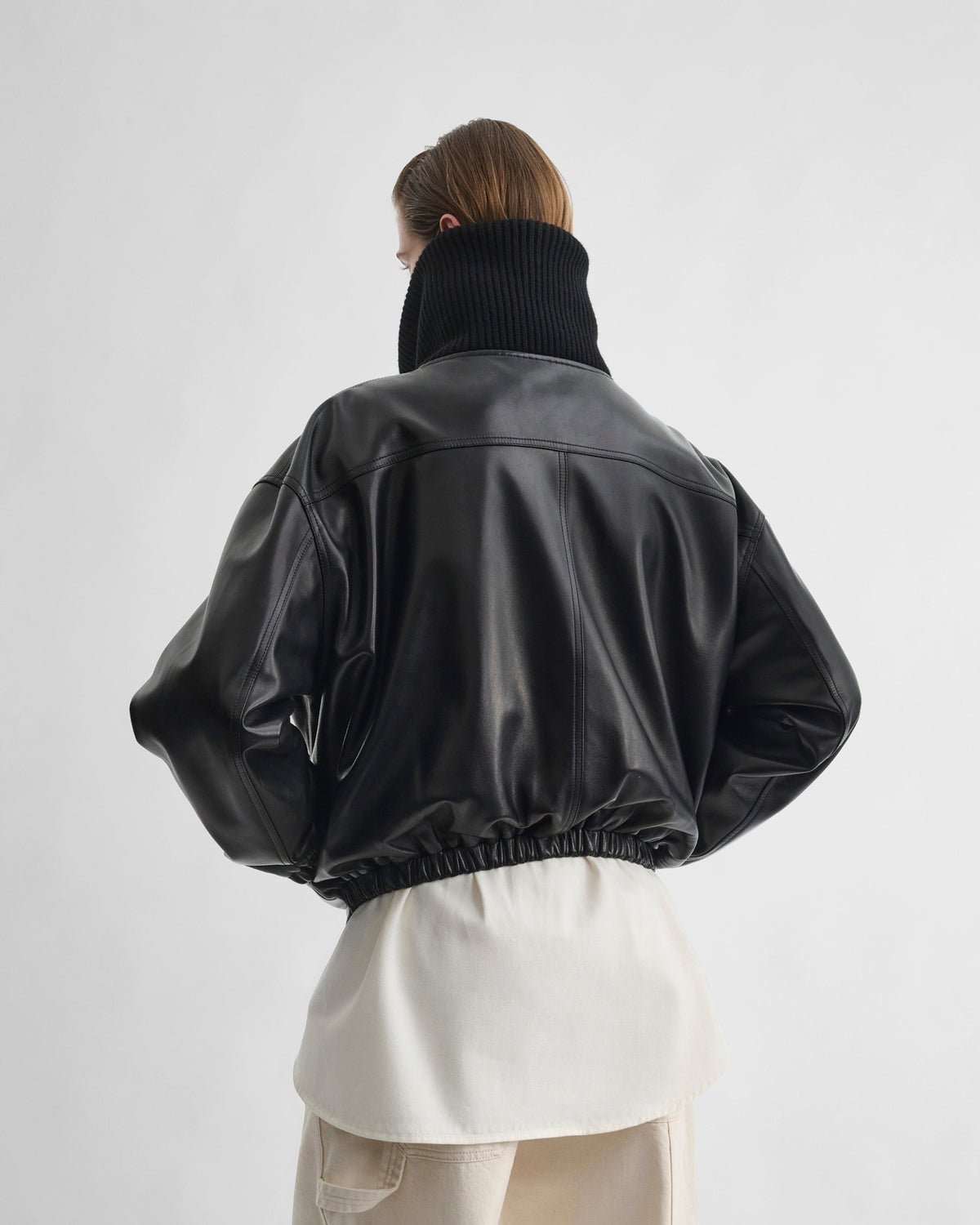 Back view of model wearing RIB NECK JACKET in black leather
