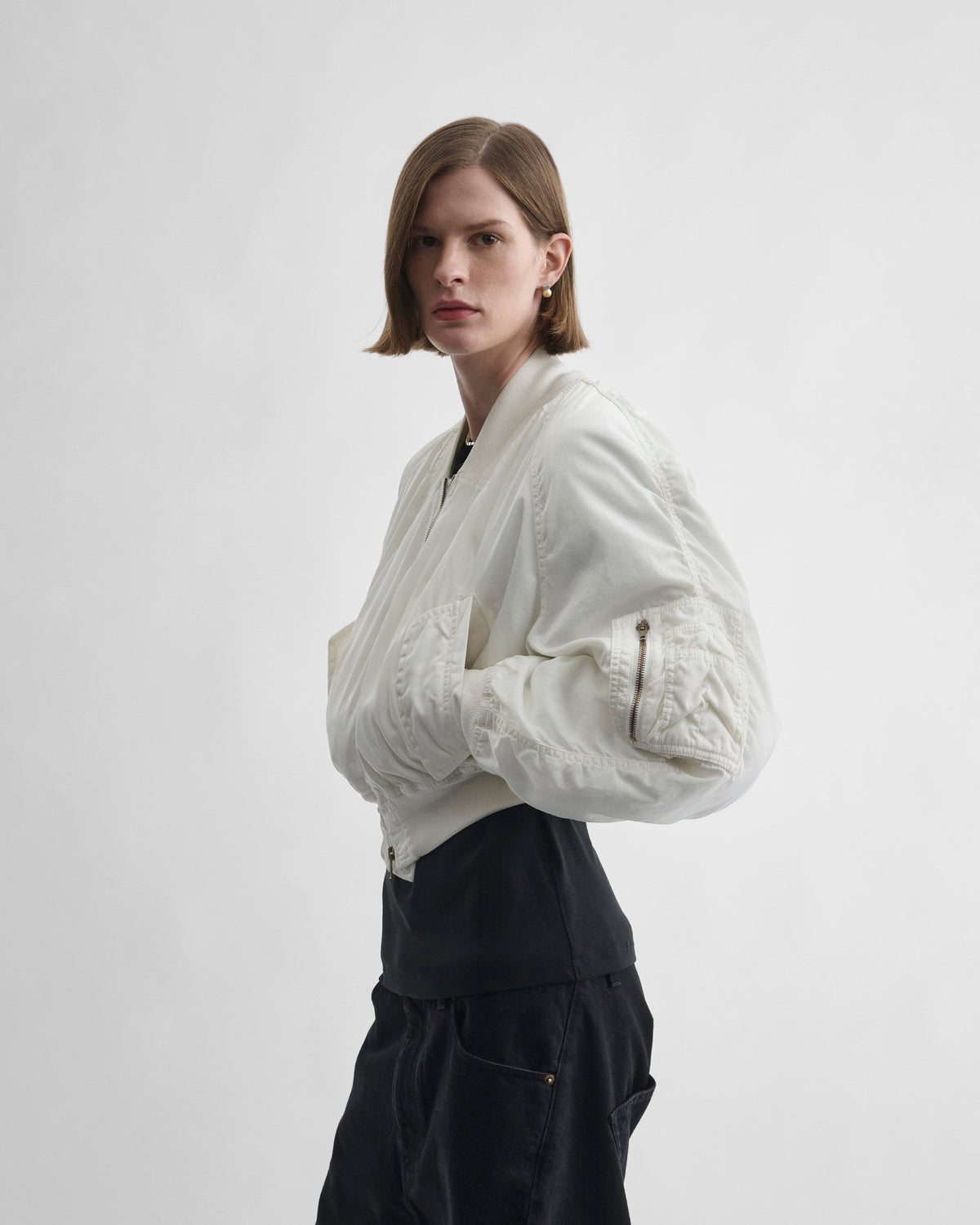 Side view of model wearing WASHED BOMBER in plaster white nylon
