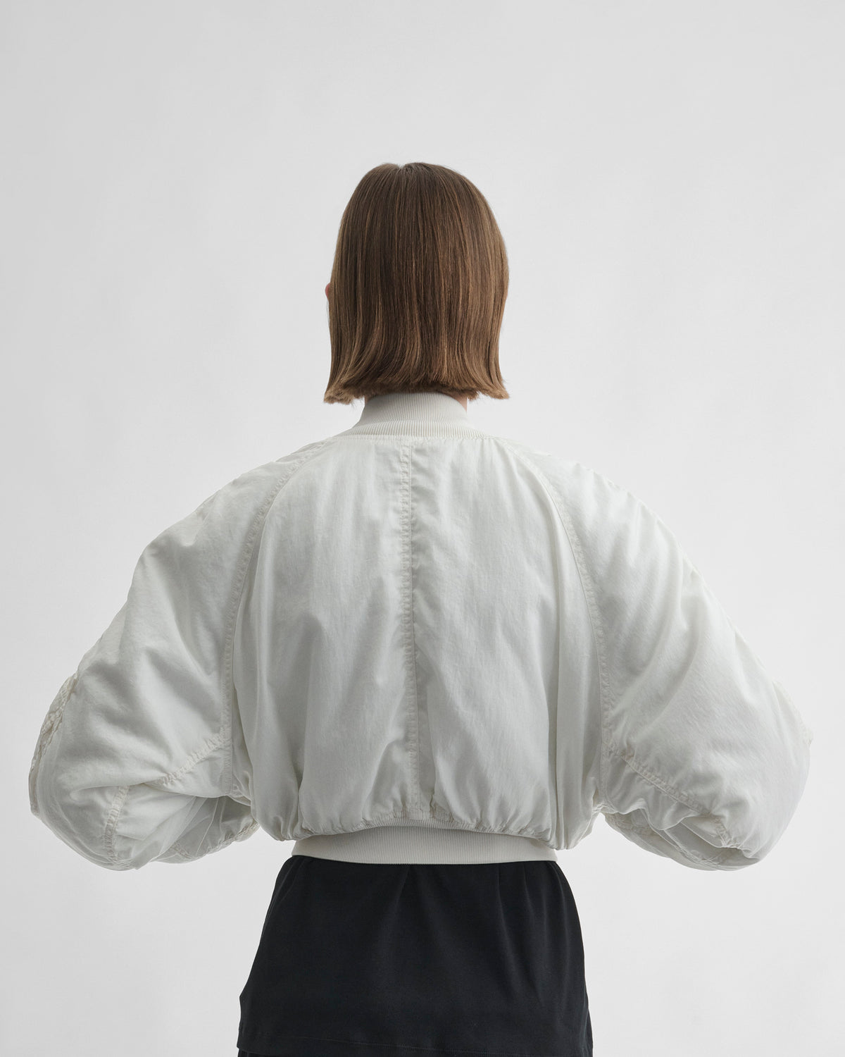 Back view of model wearing WASHED BOMBER in plaster white nylon