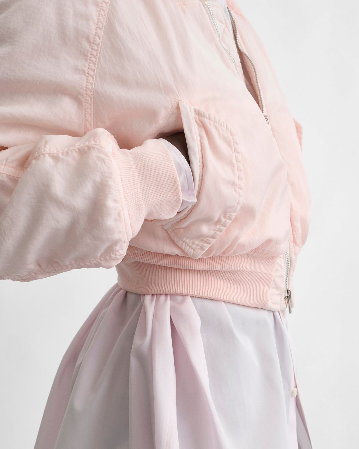 Detail view of model wearing WASHED BOMBER in pale pink nylon