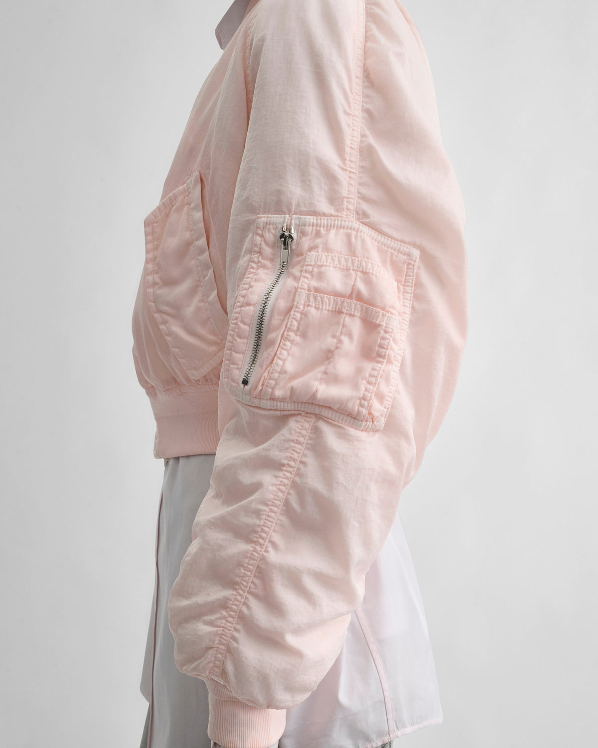Side pocket view of model wearing WASHED BOMBER in pale pink nylon