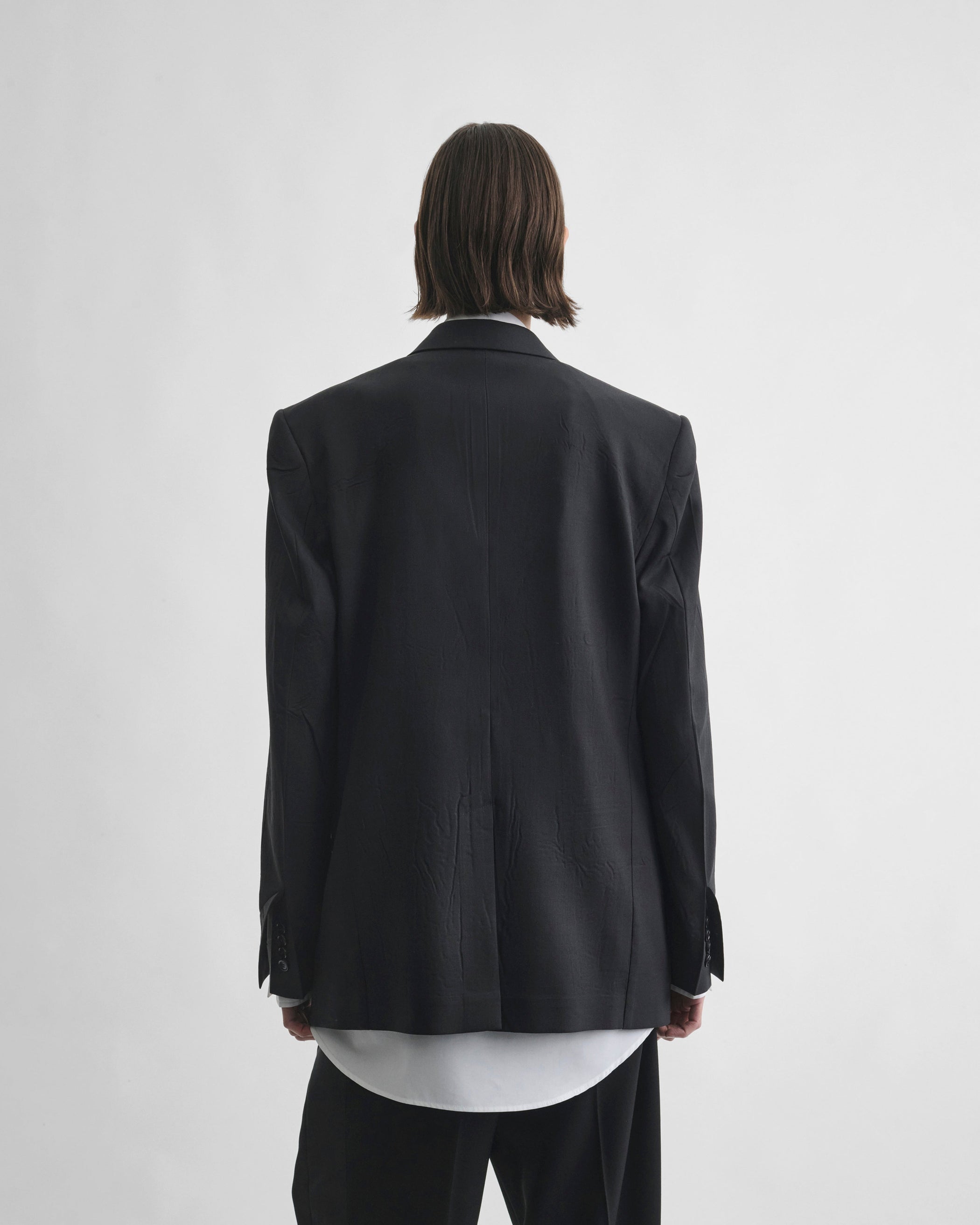 Back view of model wearing NEAPOLITAN JACKET in black wool