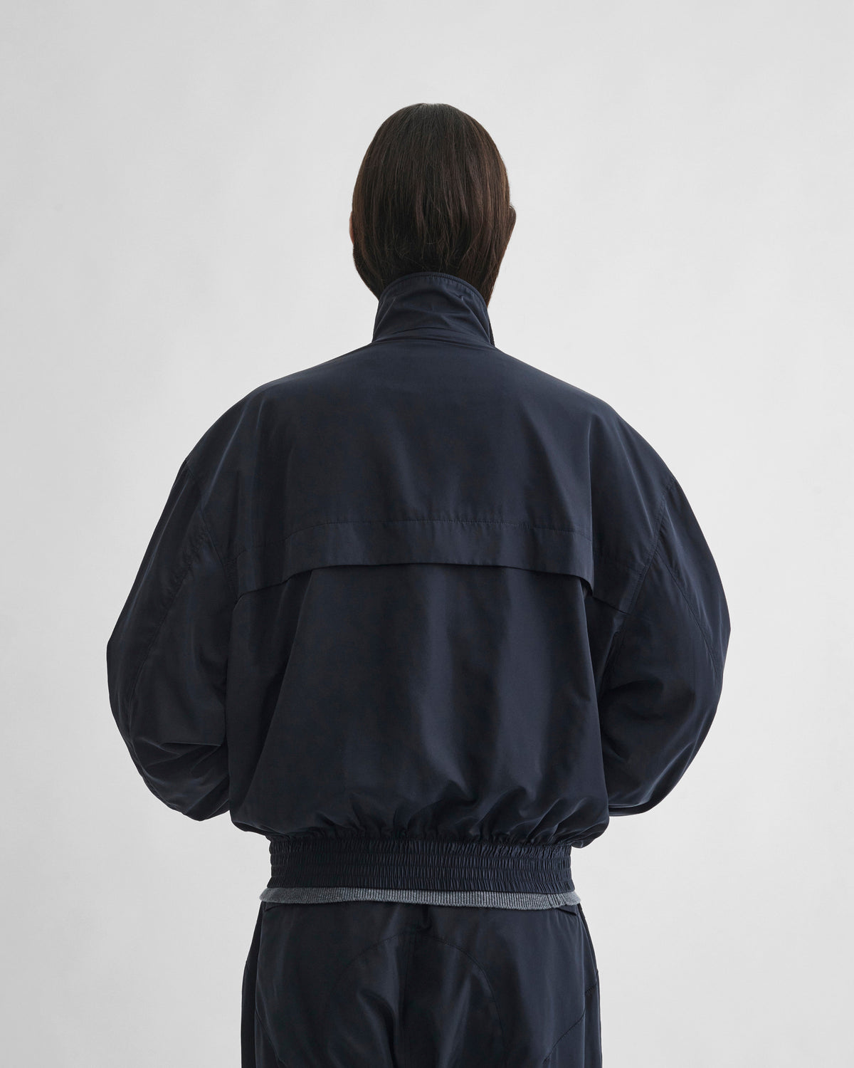 Back view of model wearing WINDBREAKER in dark navy polyester