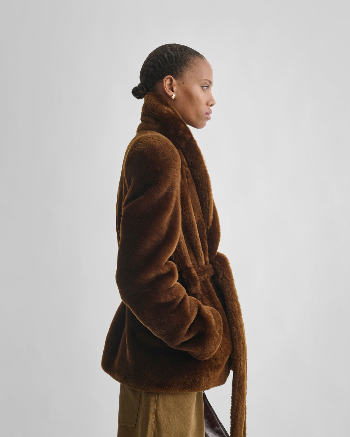 Side view of model wearing BELTED ROBE JACKET in burnt orange shearling